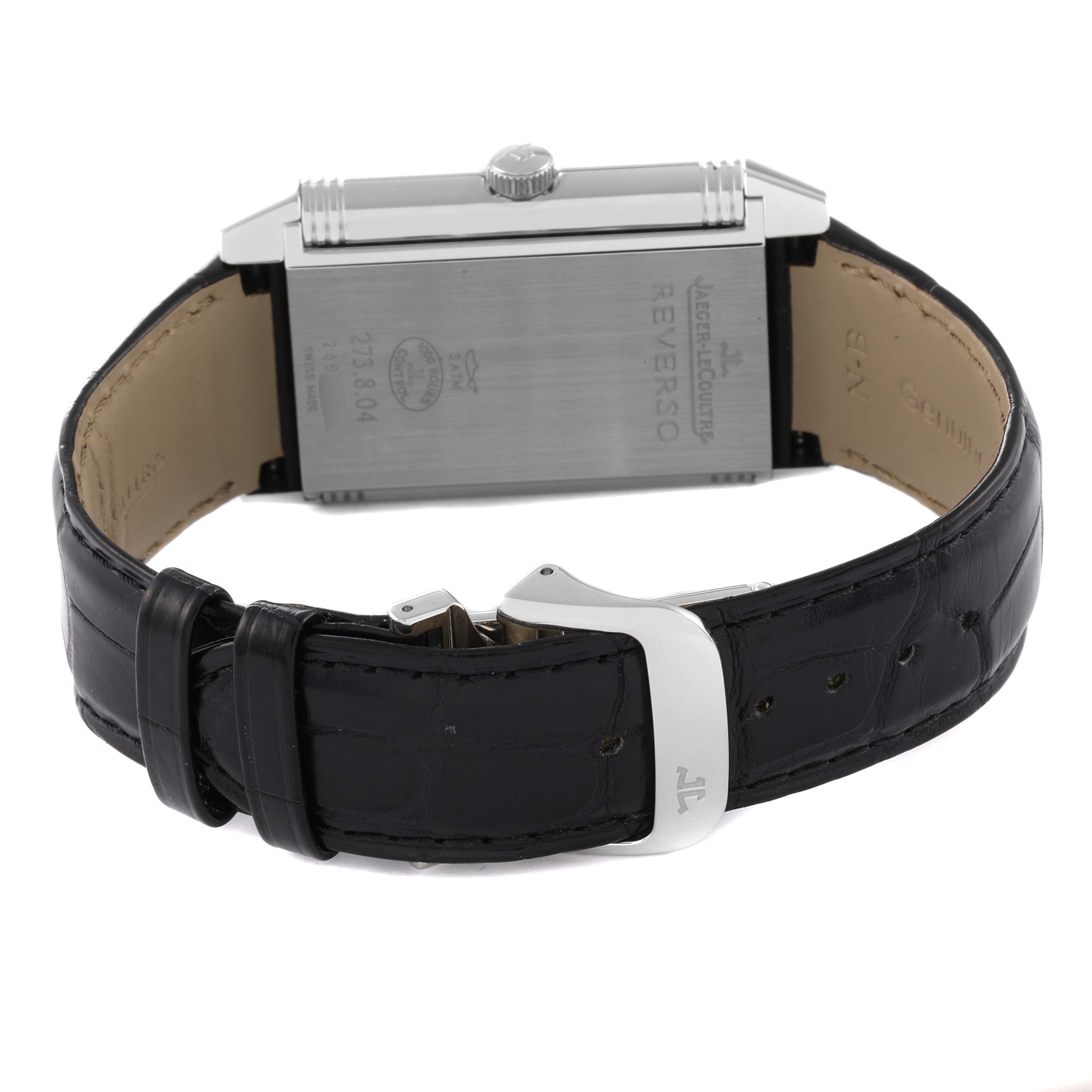 The image shows the back and side of a Jaeger-LeCoultre Reverso watch, including the case back, crown, and leather strap with buckle.