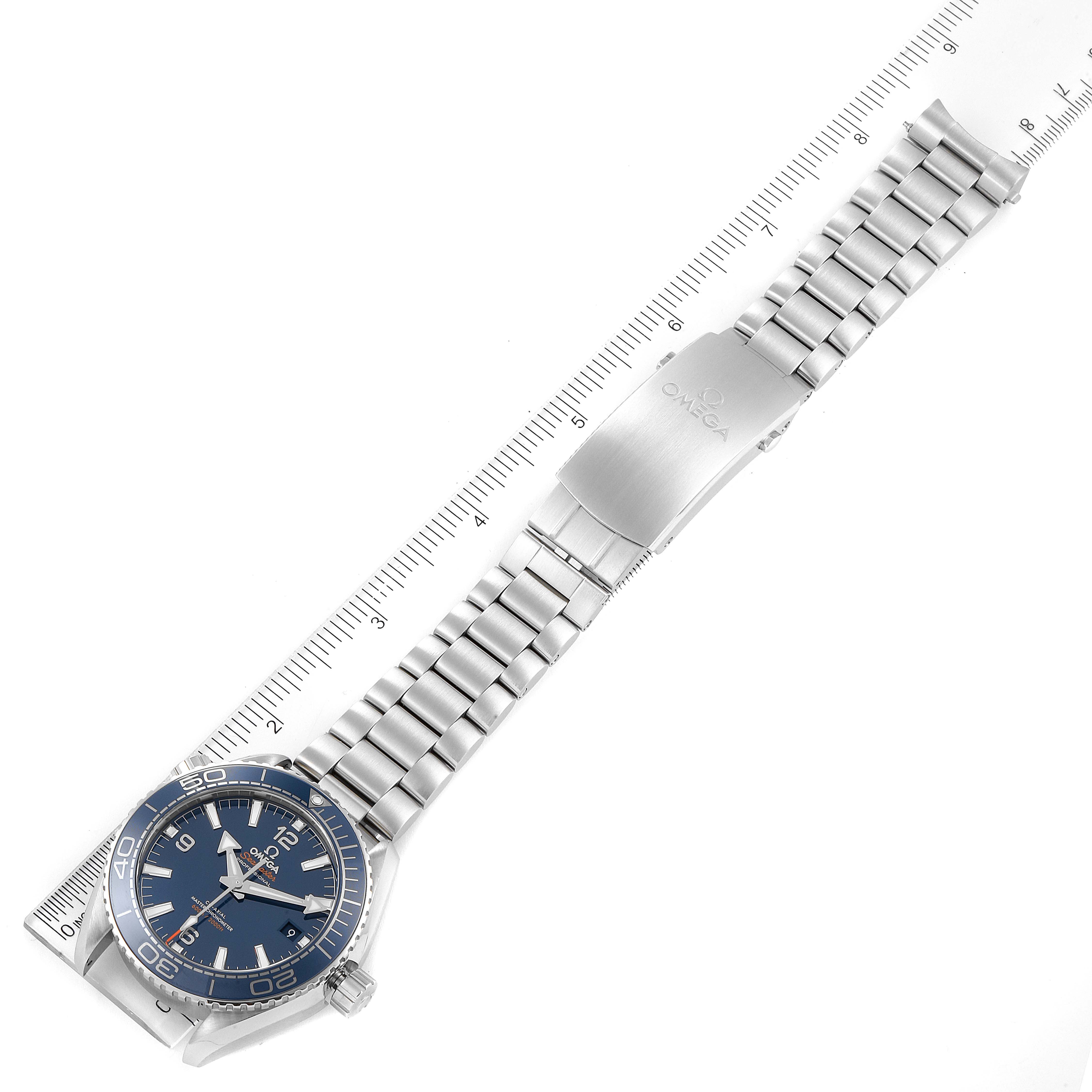 The image shows an Omega Planet Ocean 215.30.44.21.03.001 Men's Stainless Steel Blue Dial 215.30.44.21.03.001 Men's Stainless Steel Blue Dial watch laid flat, featuring its dial, bracelet, and clasp, aligned with a ruler for measurement.