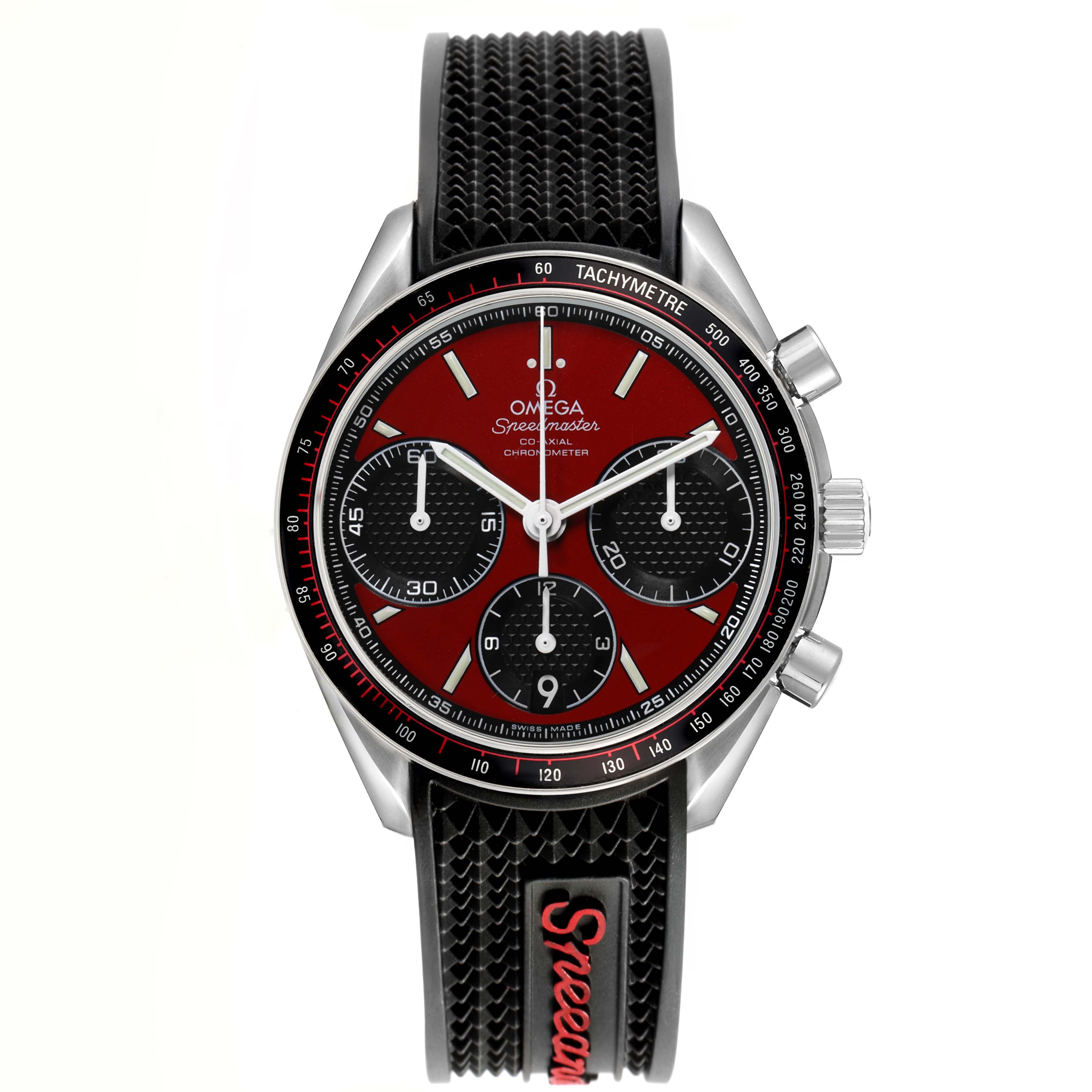 The Omega Speedmaster 326.32.40.50.11.001 Men's Stainless Steel Red Dial watch is shown from a front angle, highlighting the dial, tachymetre bezel, and textured strap.