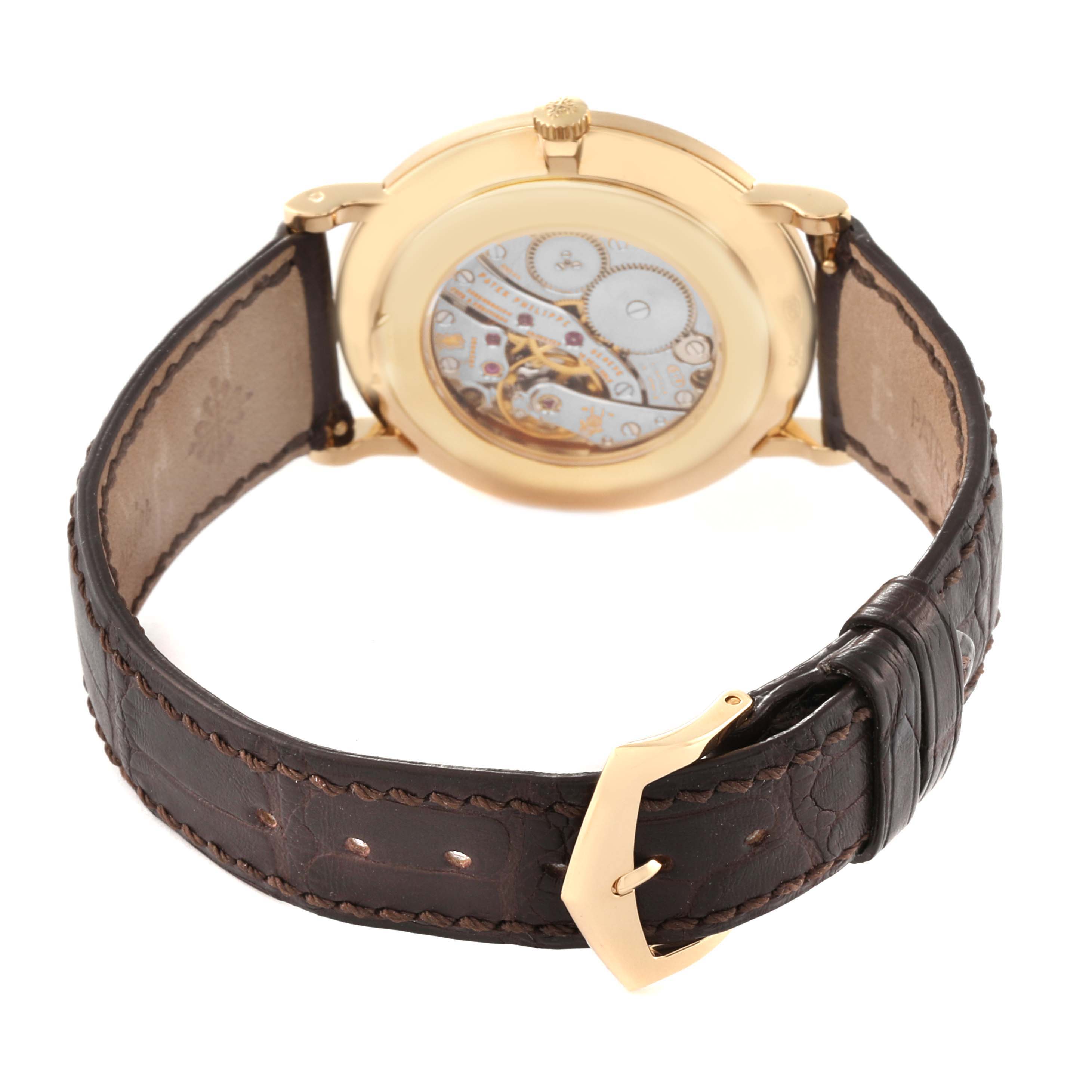 This image of a Patek Philippe Calatrava 5119J Men's Yellow Gold White Dial 5119J Men's Yellow Gold White Dial watch shows the back case and part of the brown leather strap from an angled rear view.