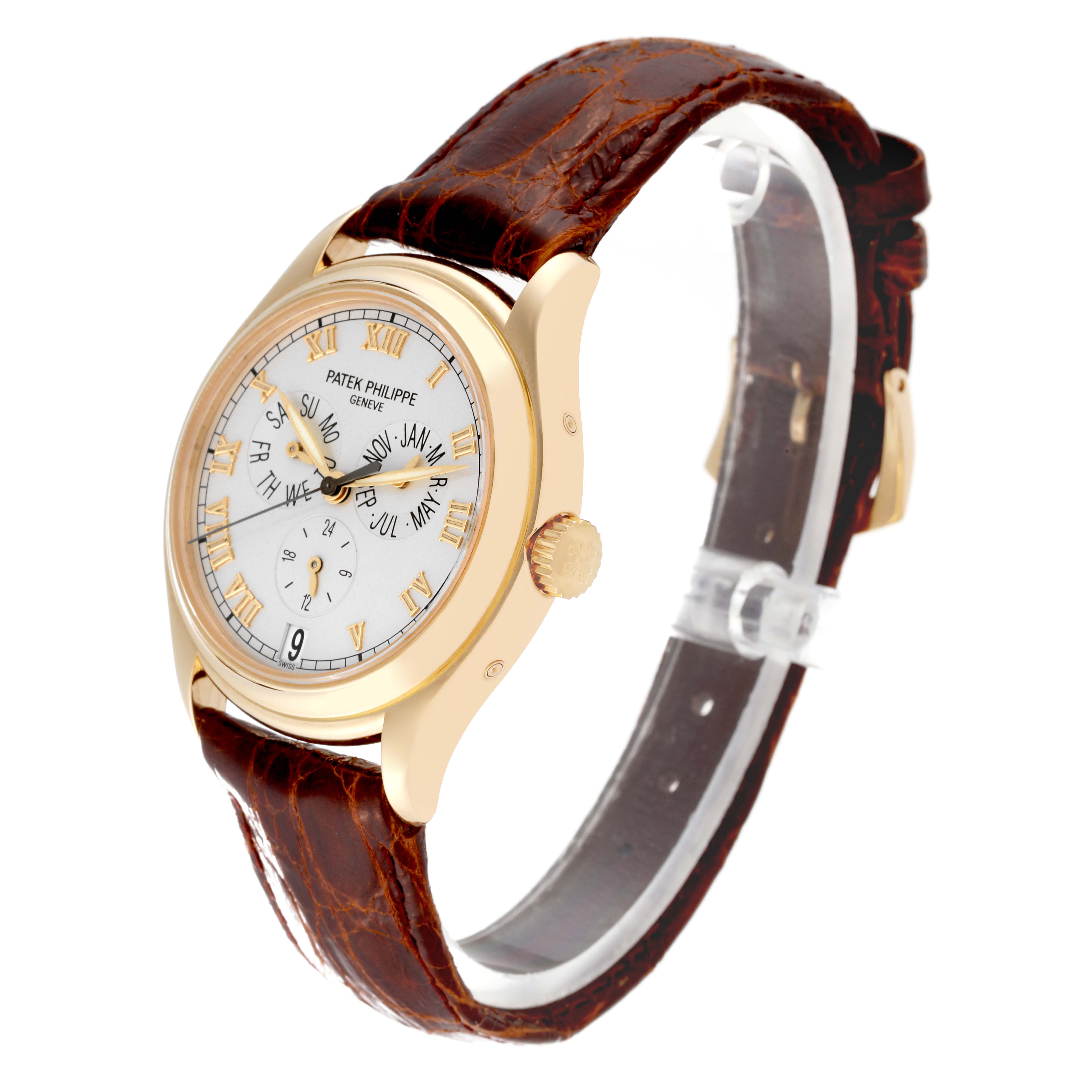 The image shows a side angle view of a Patek Philippe Complications 5035J-001 Men
s Yellow Gold Silver Dial 5035J-001 Men
s Yellow Gold Silver Dial model watch with a leather strap and a gold case.