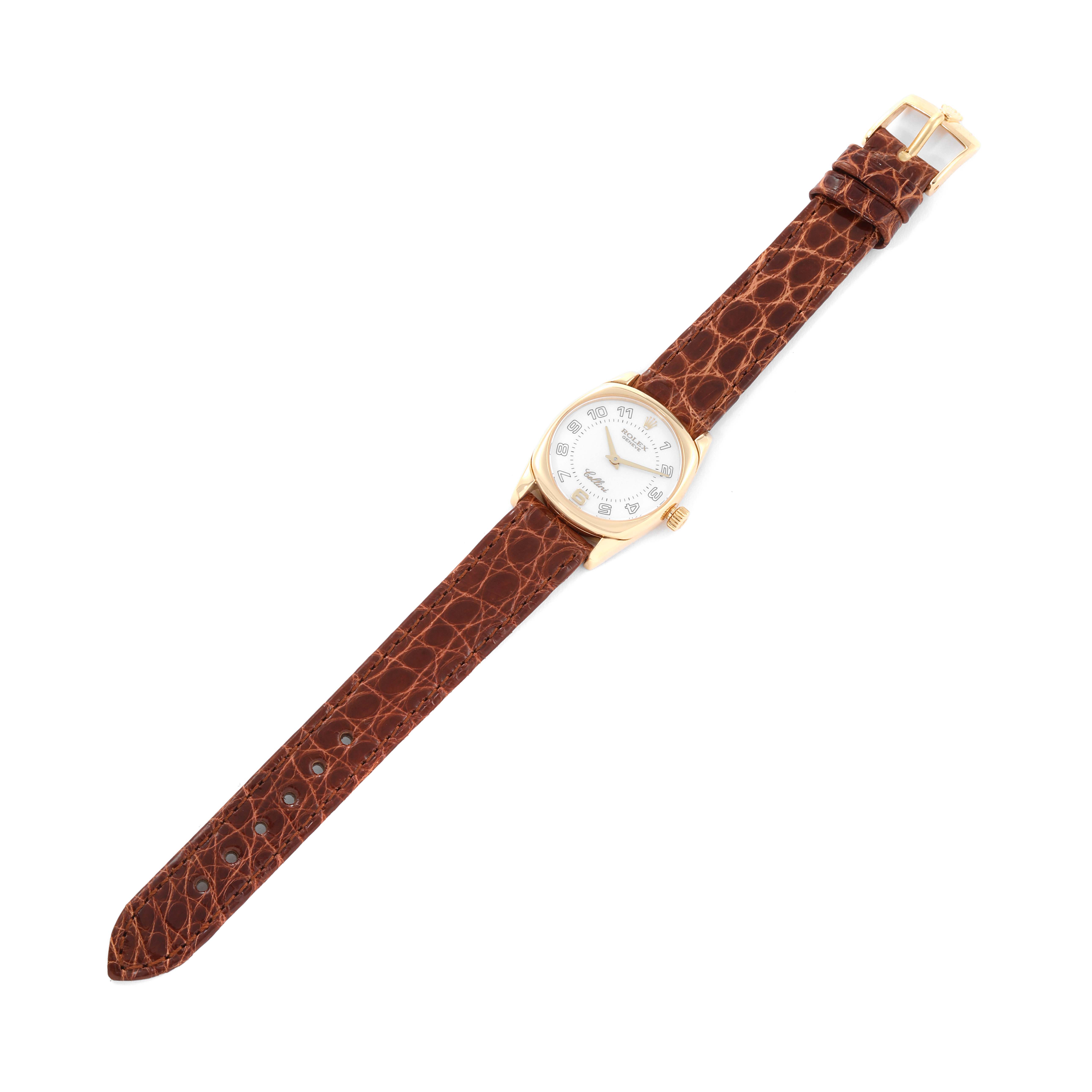 The Rolex Cellini 6229 Women's Yellow Gold White Dial 6229 Women's Yellow Gold White Dial watch is shown from an overhead angle, displaying its white dial, gold case, and brown leather strap with a buckle.