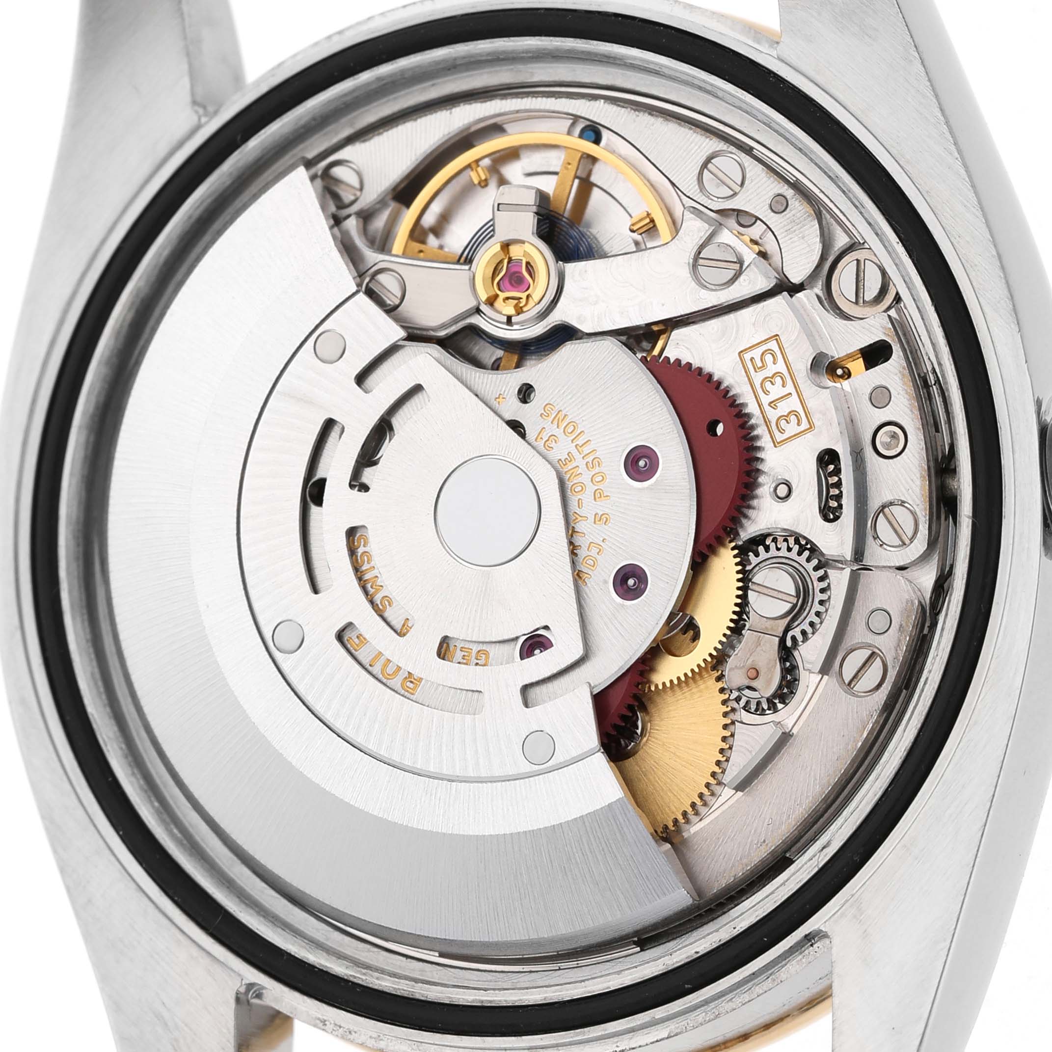 The image shows the movement of a Rolex Datejust 116243 Men's Stainless Steel Champagne Dial watch from a back angle, displaying its intricate gears and mechanisms.