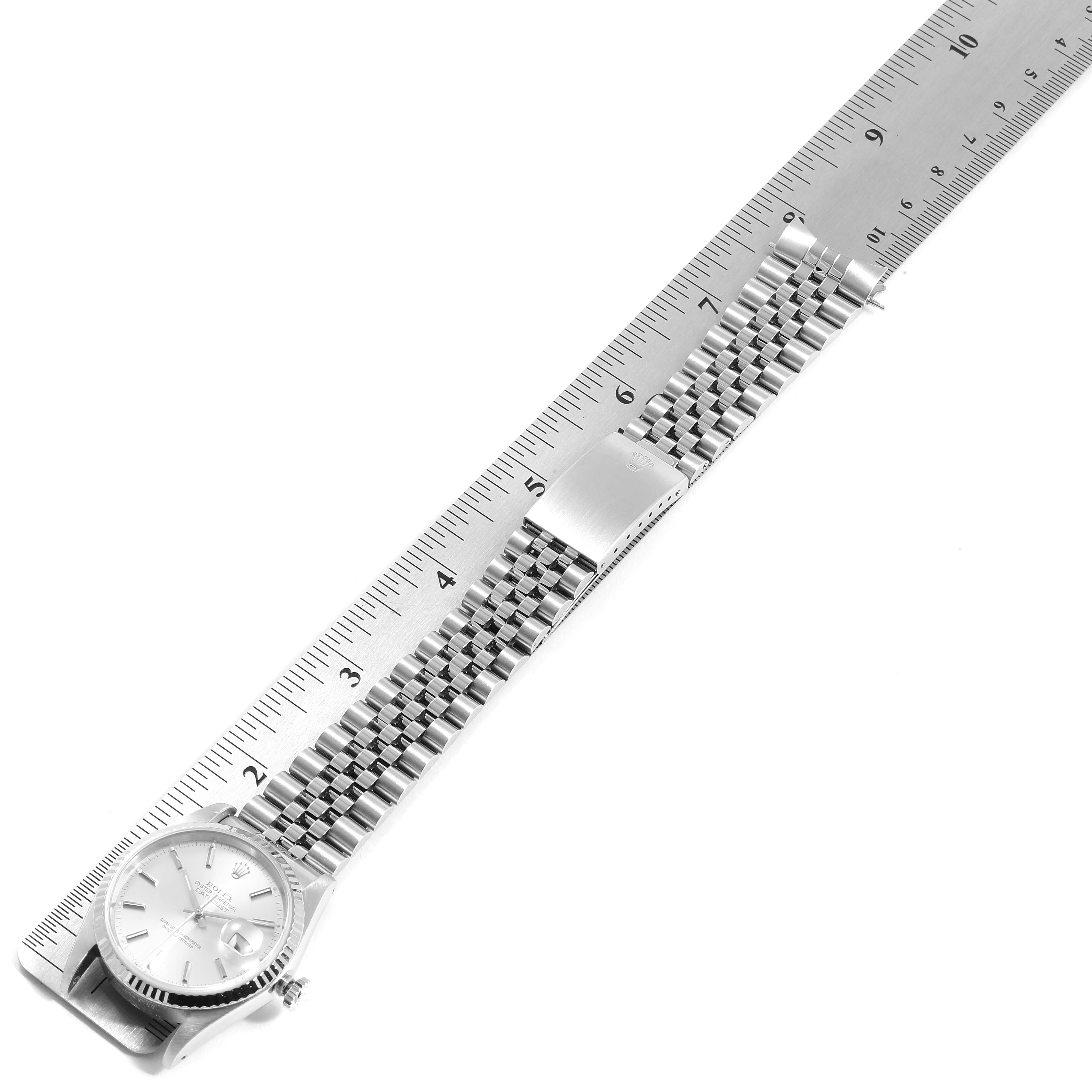 The Rolex Datejust 16234 Men's Stainless Steel Silver Dial 16234 Men's Stainless Steel Silver Dial watch is shown fully extended with its dial and bracelet laid along a measurement ruler at an oblique angle.