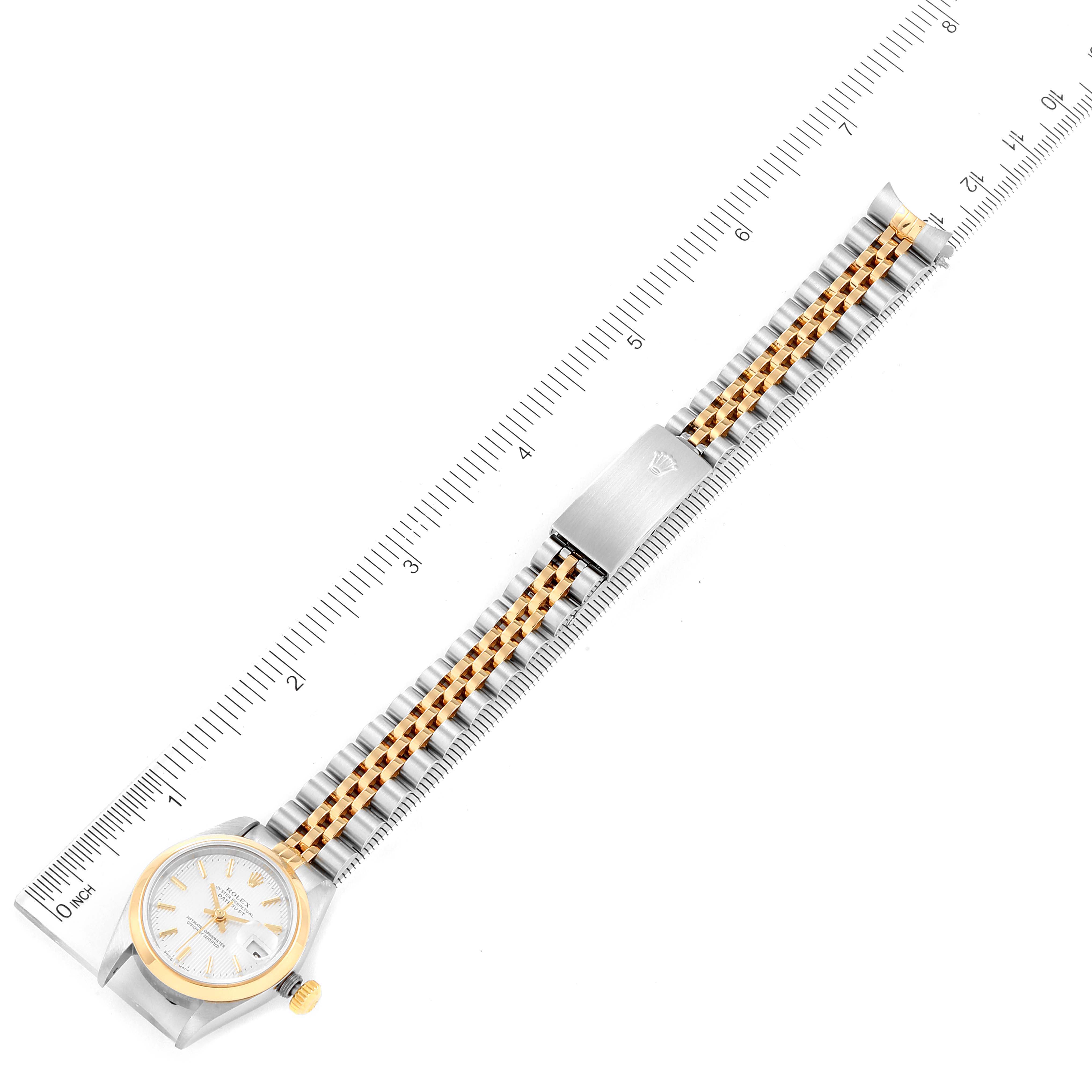 This image shows a Rolex Datejust 79163 Women's Steel and Gold (two tone) Silver Dial 79163 Women's Steel and Gold (two tone) Silver Dial model watch placed flat with the full bracelet and rulers for size reference.
