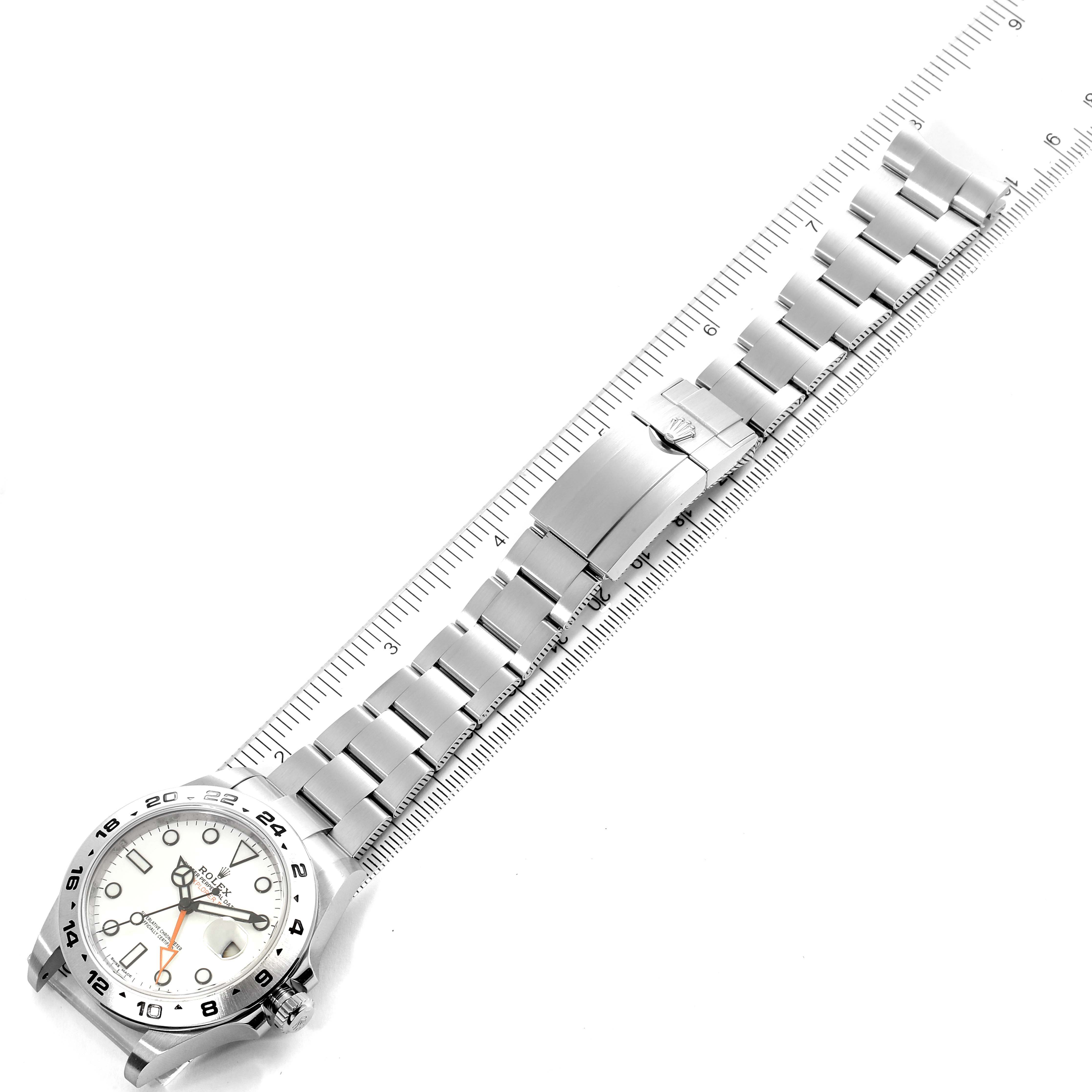 The Rolex Explorer 216570 Men's Stainless Steel White Dial 216570 Men's Stainless Steel White Dial watch is shown from an aerial view, displaying the face, bracelet, and clasp alongside a measuring ruler.