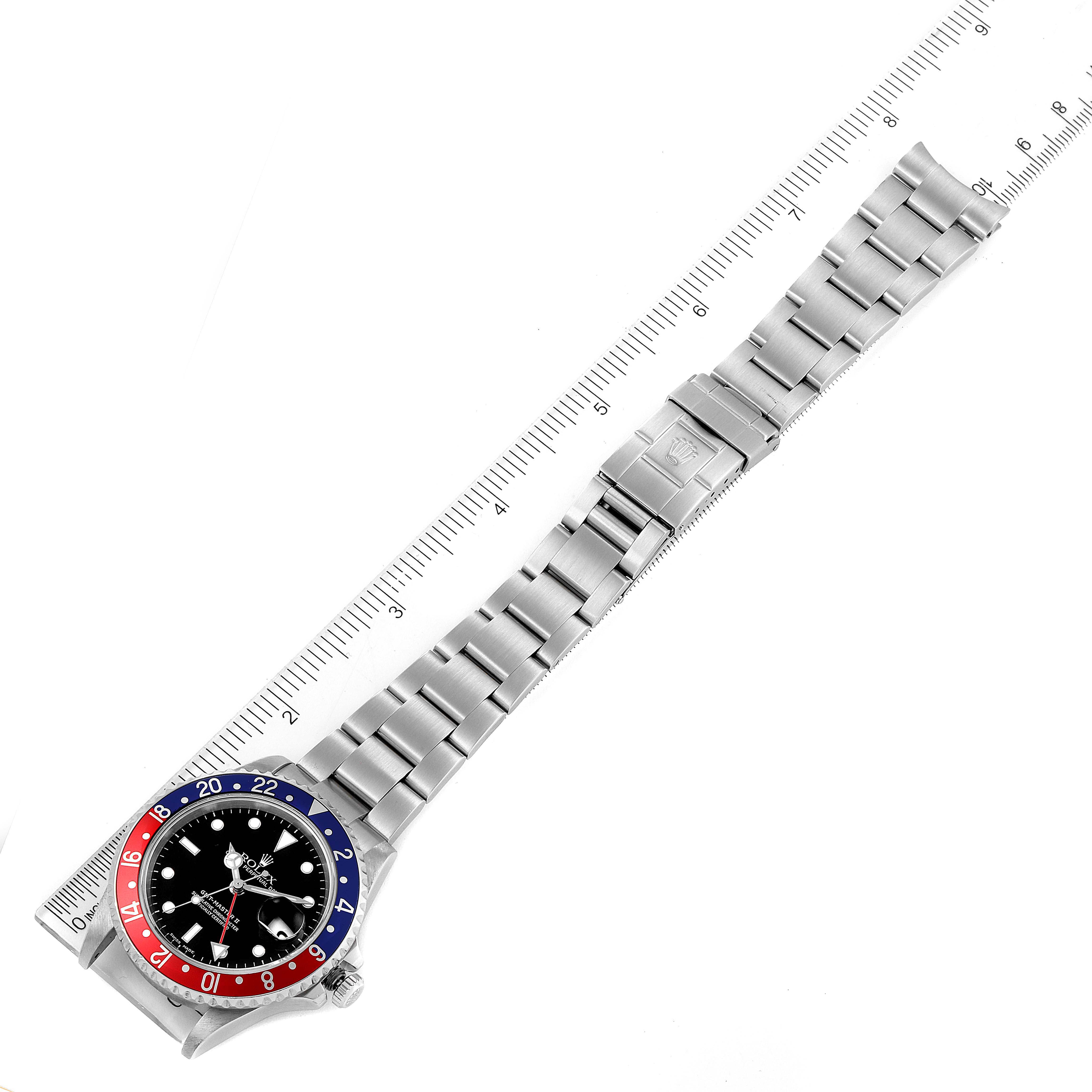 The image shows a top-down view of a Rolex GMT-Master 16710 Men
s Stainless Steel Black Dial 16710 Men
s Stainless Steel Black Dial watch with focus on the full bracelet, clasp, and bezel next to a ruler.