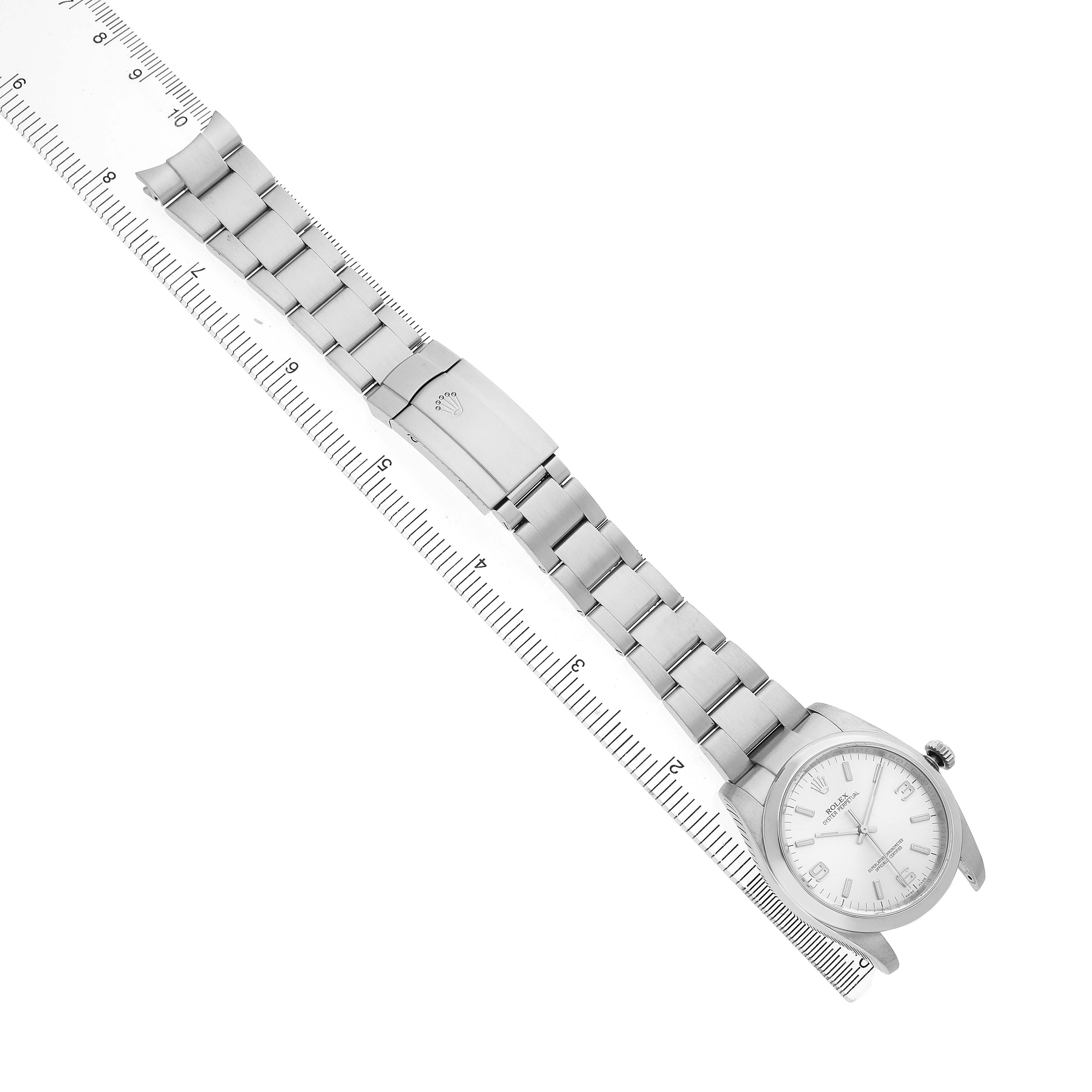 The image shows a Rolex Oyster Perpetual 116000 Men's Stainless Steel Silver Dial watch laid flat, highlighting the bracelet and clasp alongside a ruler for scale.