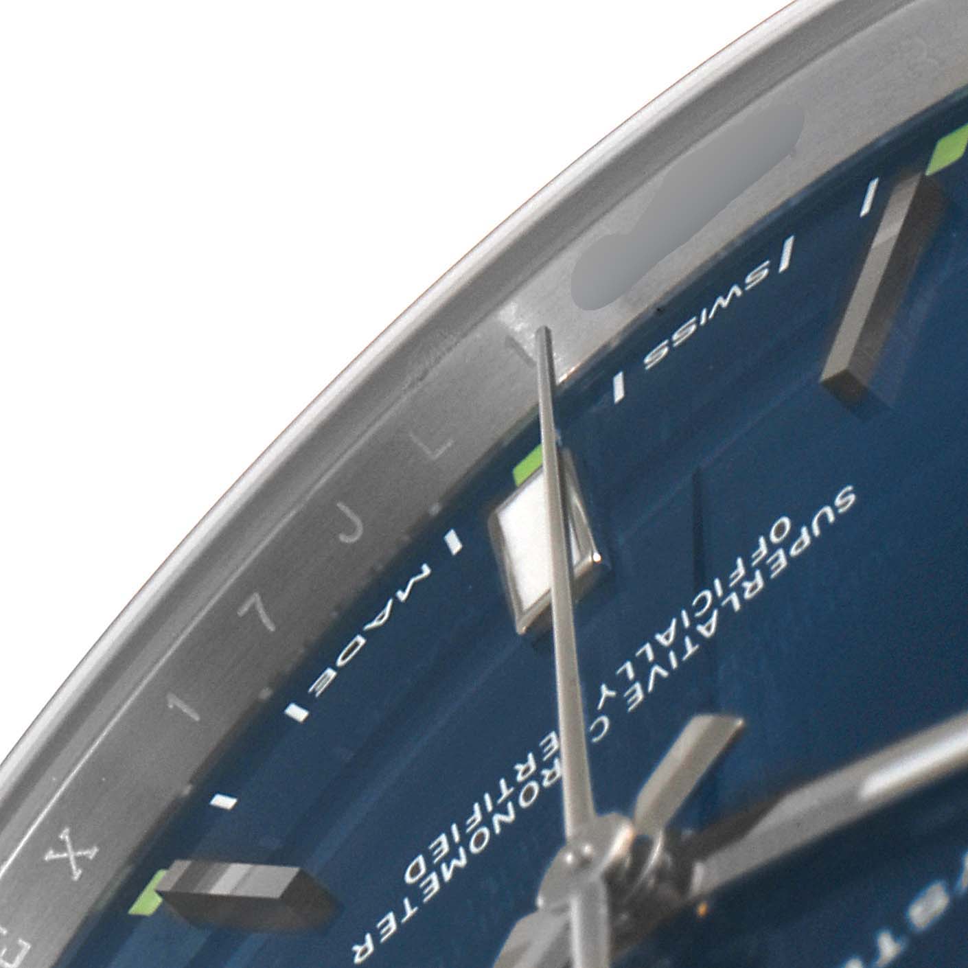 The image shows a close-up of the dial and bezel of a Rolex Oyster Perpetual 114300 Men
s Stainless Steel Blue Dial 114300 Men
s Stainless Steel Blue Dial watch, focusing on the hour markers and hands.