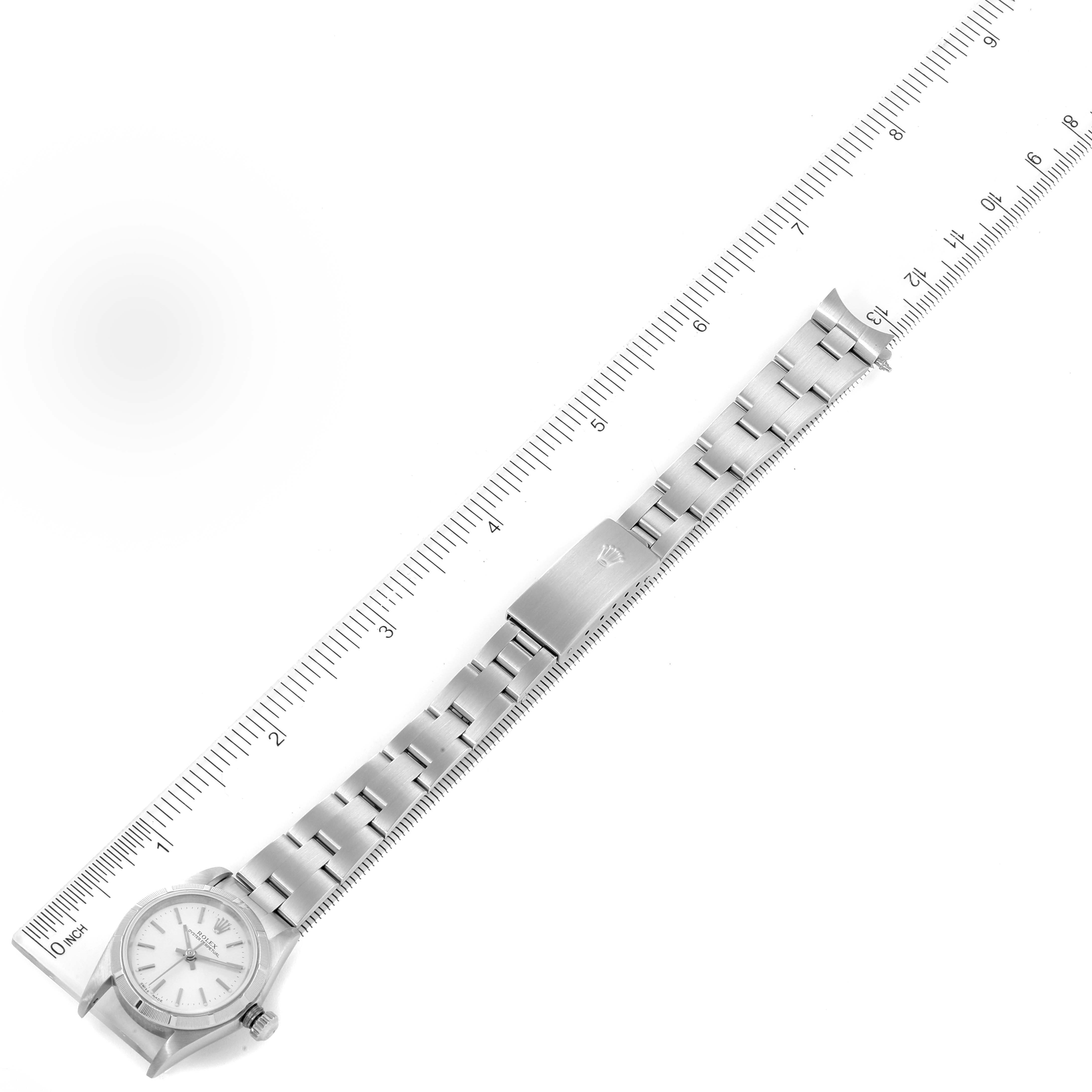 The image shows a full-length view of a Rolex Oyster Perpetual 76030 Women
s Stainless Steel Silver Dial 76030 Women
s Stainless Steel Silver Dial watch, including the watch face, bracelet, and clasp, alongside a ruler.