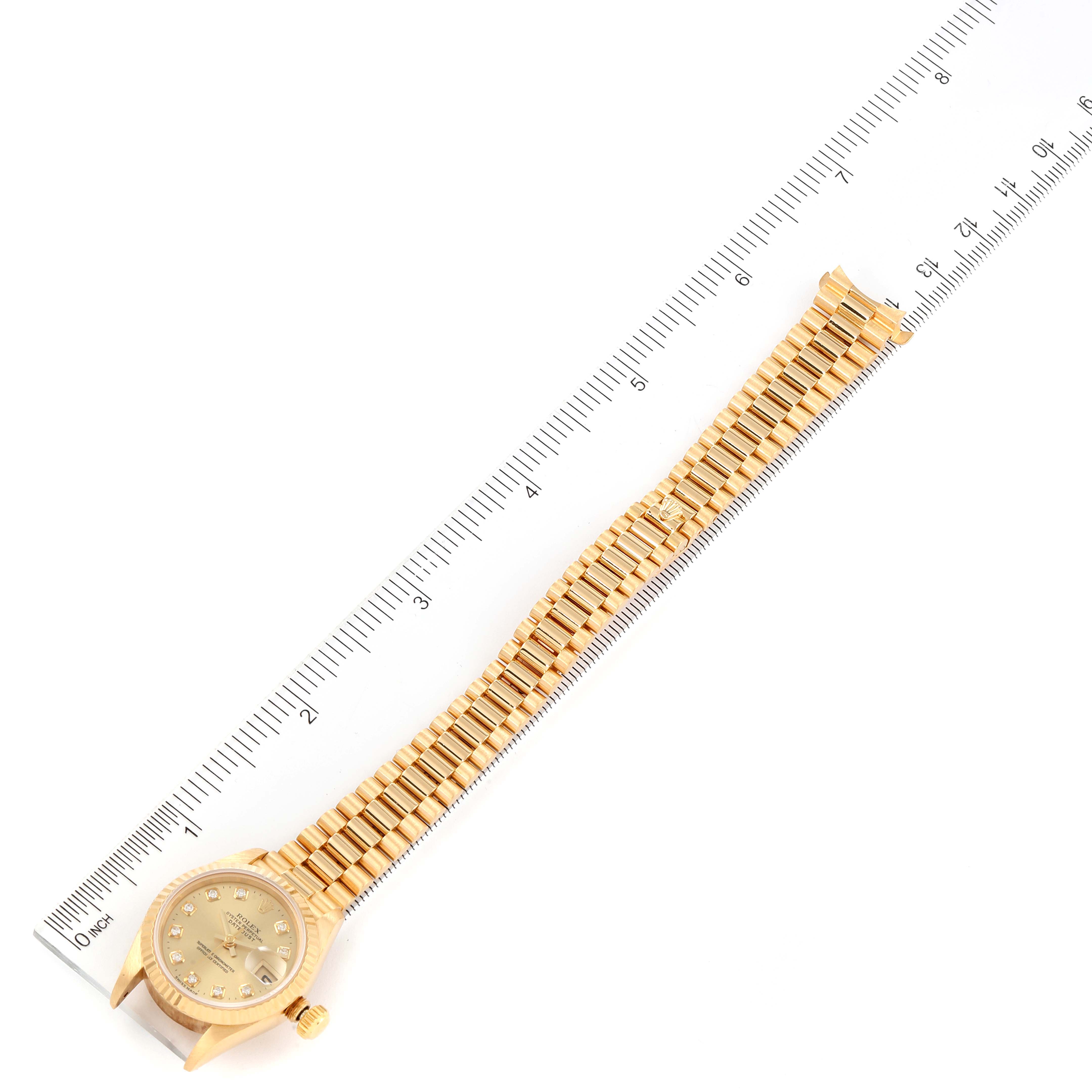 This image shows a gold Rolex President 69178 Women
s Yellow Gold Champagne Dial 69178 Women
s Yellow Gold Champagne Dial model watch laid flat next to a ruler for measurement.