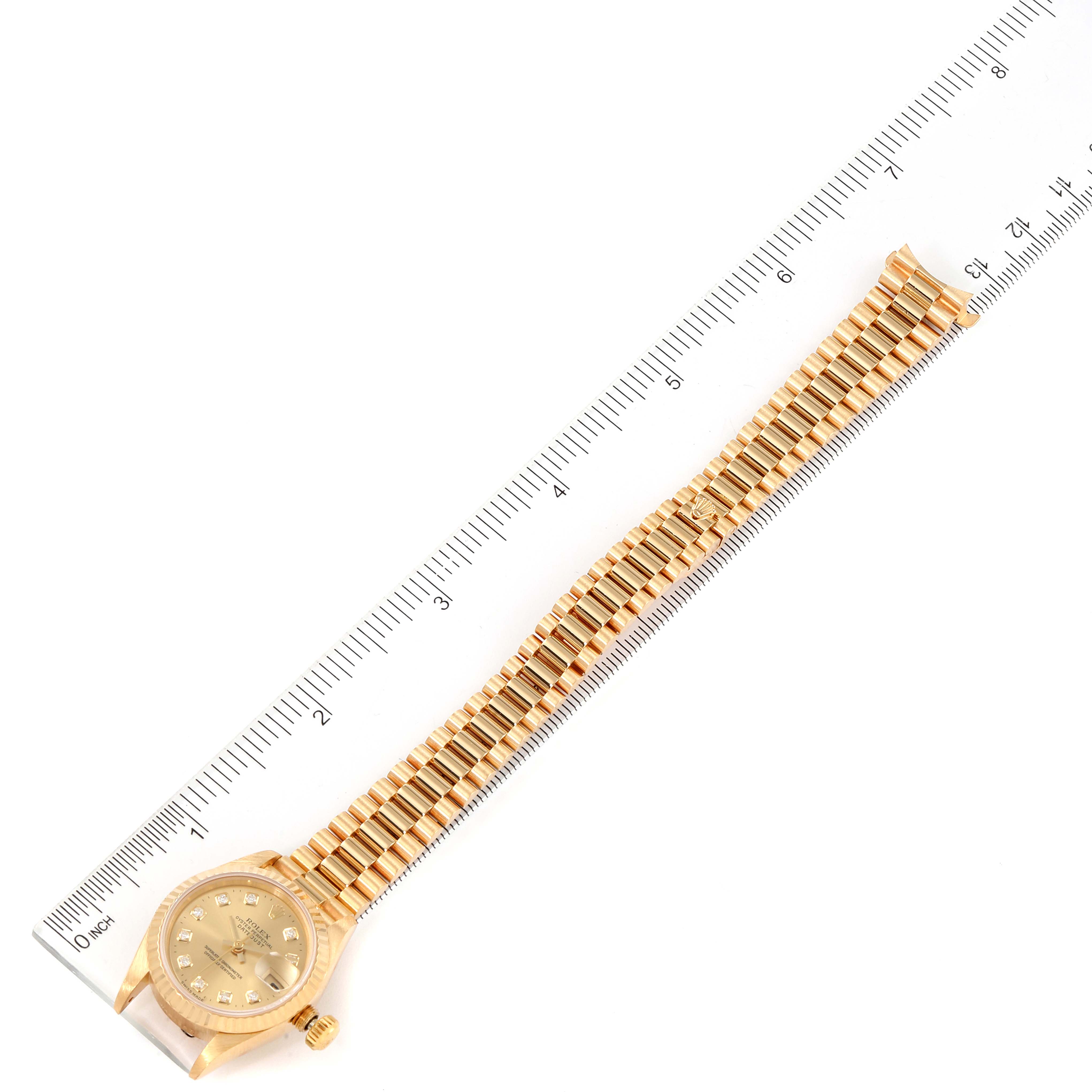 The Rolex President 69178 Women
s Yellow Gold Champagne Dial 69178 Women
s Yellow Gold Champagne Dial model watch is shown from a top-down angle with its band extended alongside a ruler.