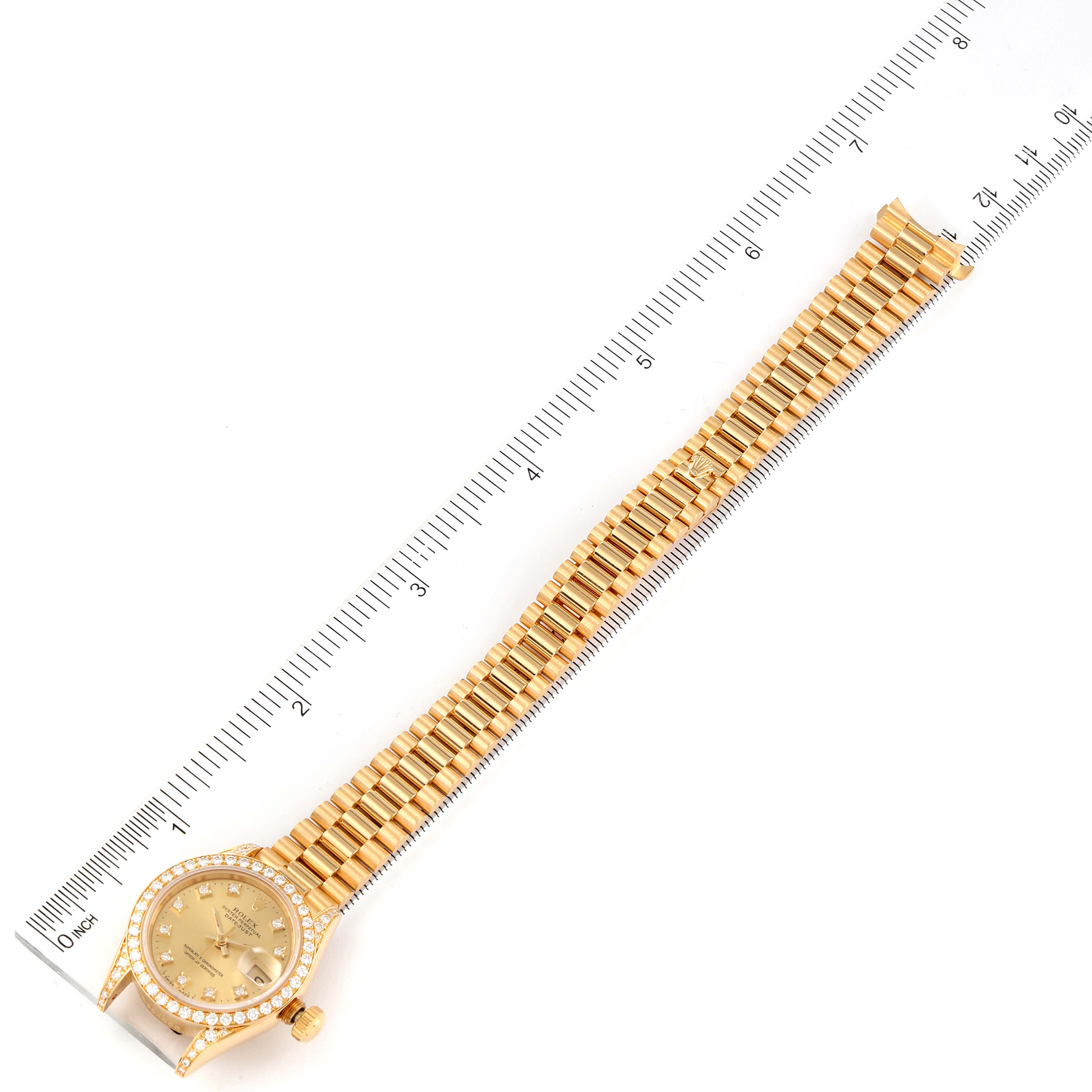 This image shows a Rolex President 69158 Women
s Yellow Gold Champagne Dial 69158 Women
s Yellow Gold Champagne Dial model watch laid flat next to a ruler for measurement.