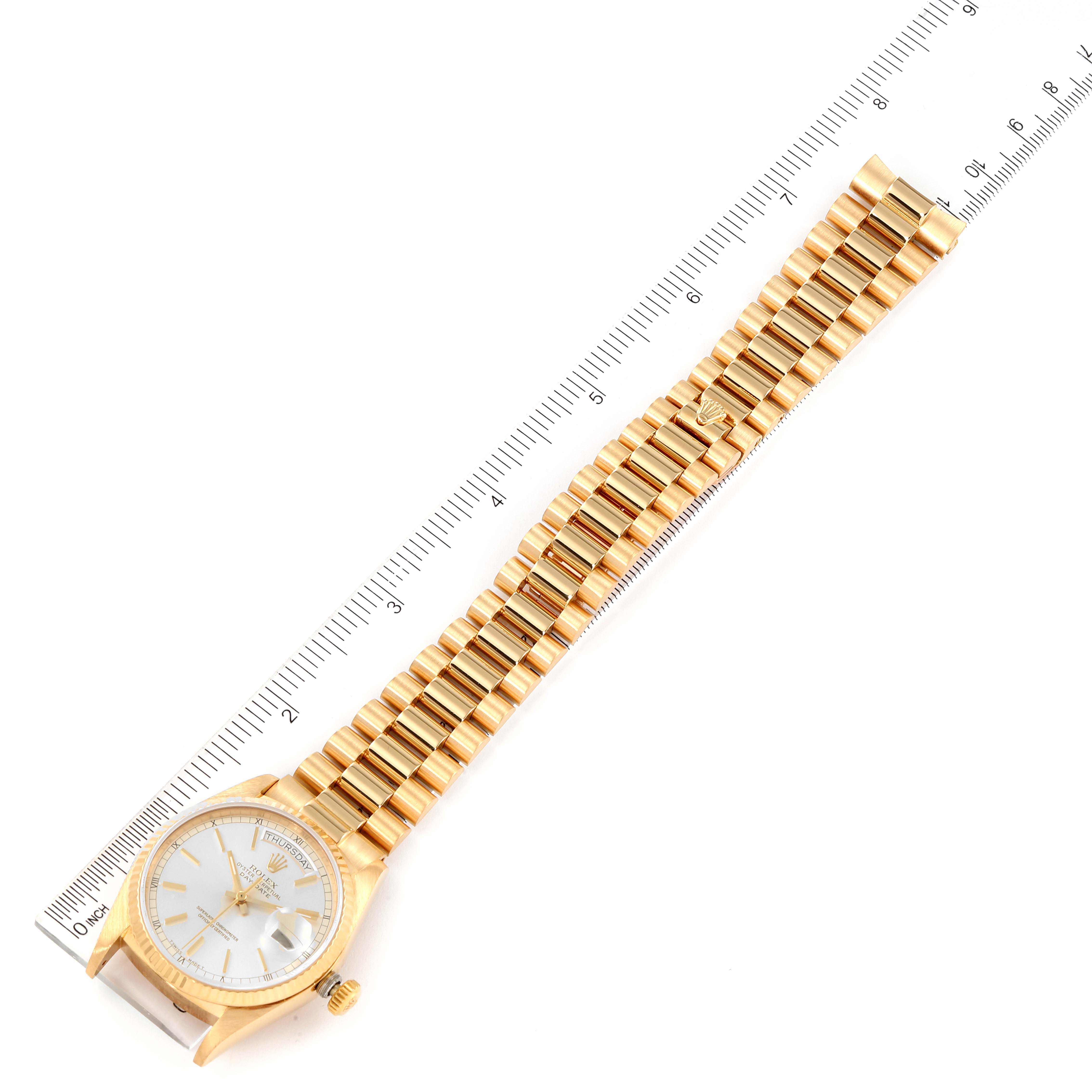 The image shows a flat-lay angle of a gold Rolex President 18038 Men's Yellow Gold Silver Dial 18038 Men's Yellow Gold Silver Dial watch with its bracelet aligned next to a measuring ruler.