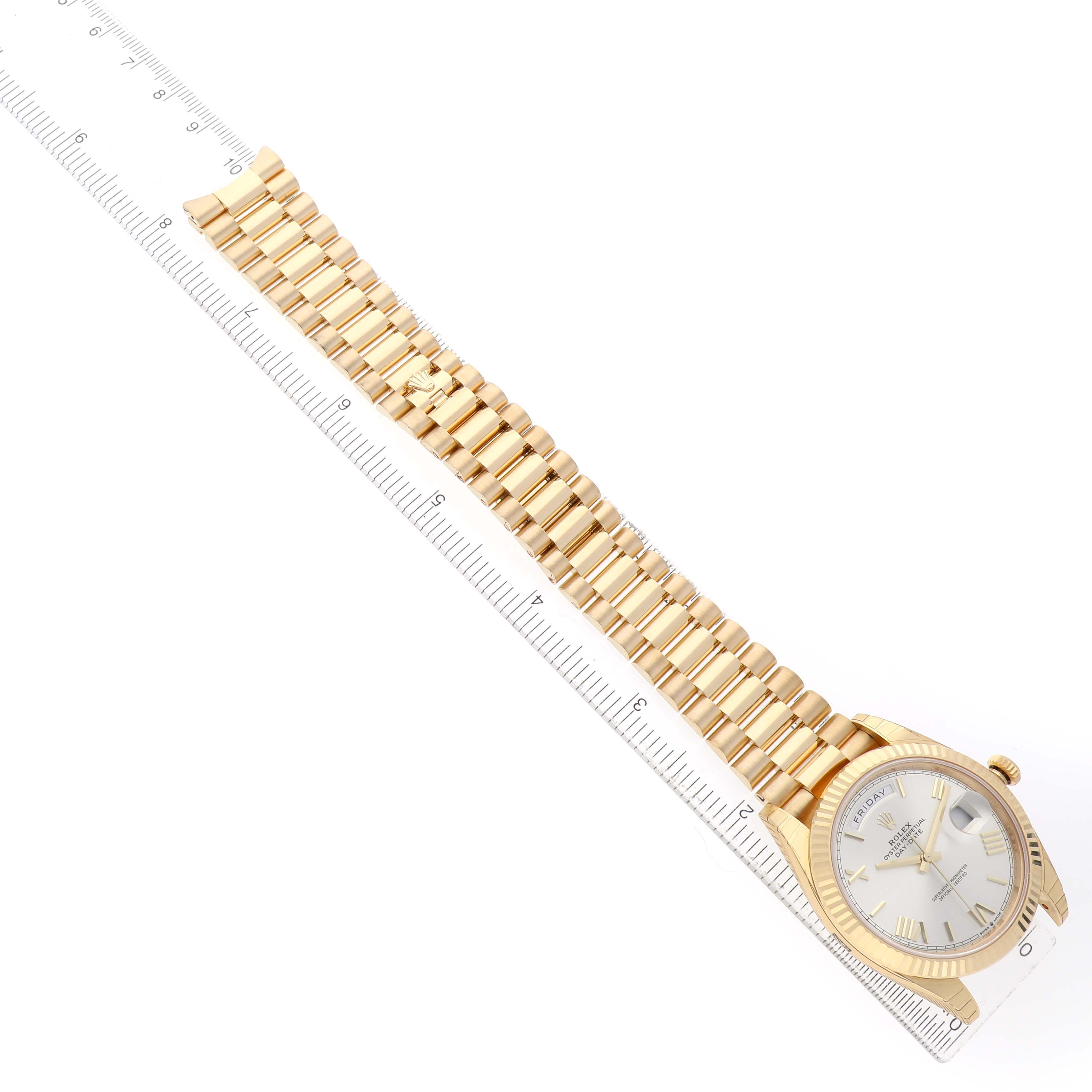 The image shows a top-down view of the Rolex President 228238 Men's Yellow Gold Silver Dial model, highlighting the full bracelet and dial, alongside a ruler for scale.