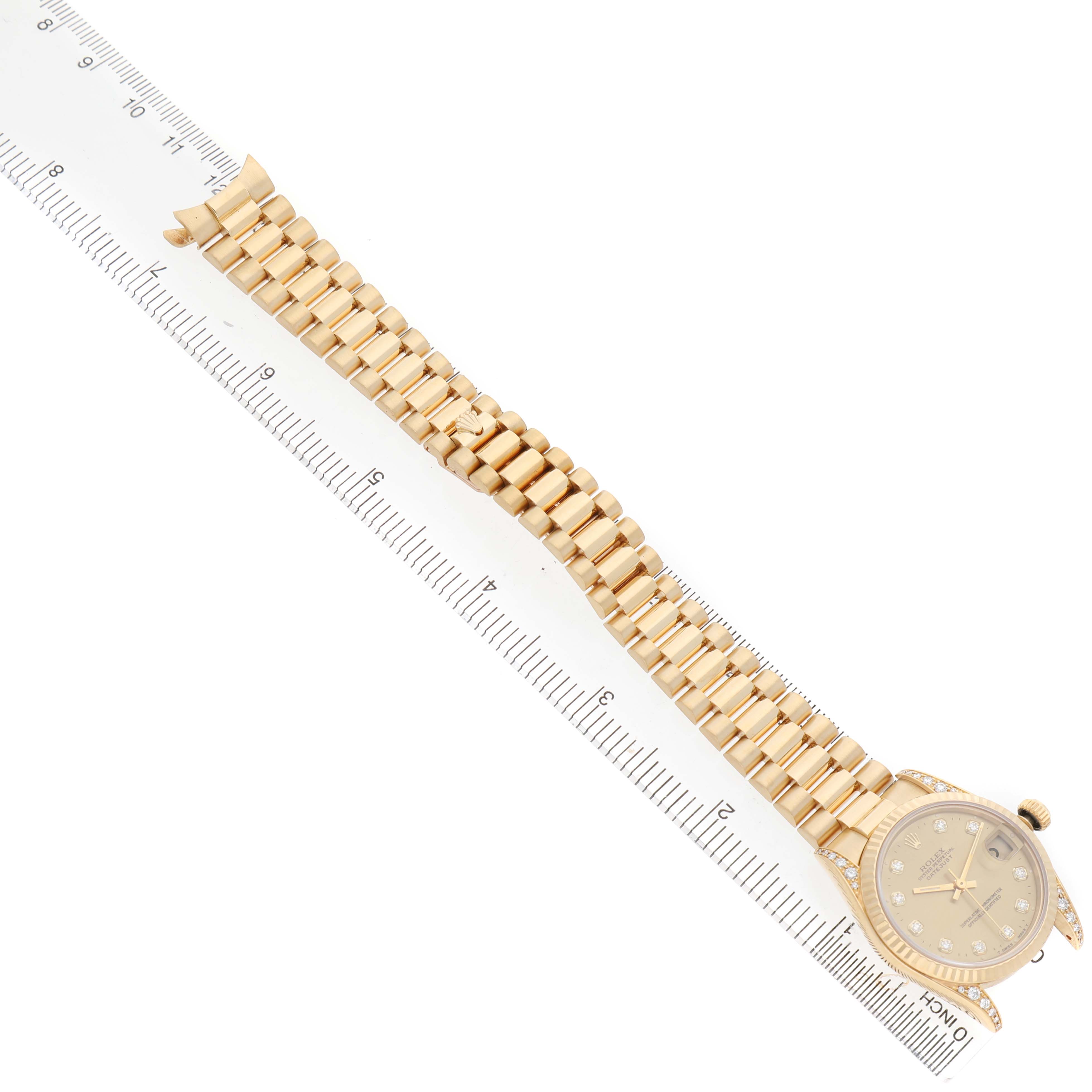 The Rolex Datejust 68238 Women's Yellow Gold Champagne Dial watch is shown from a top view, displaying its full bracelet and face alongside a ruler for scale.