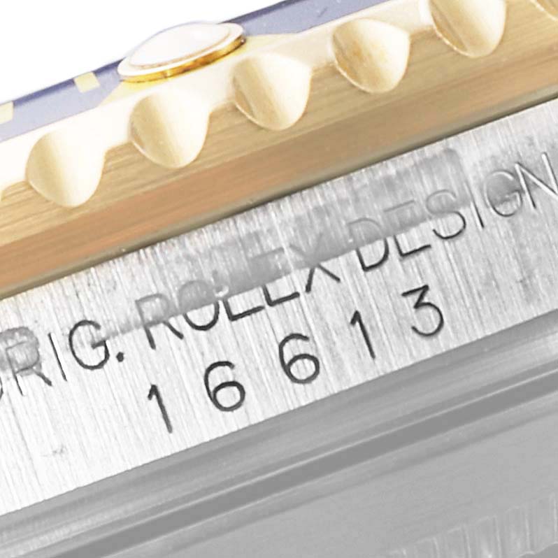 The image shows a close-up of the side of a Rolex Submariner 16613 Men
s Steel and Gold (two tone) Blue Dial 16613 Men
s Steel and Gold (two tone) Blue Dial watch, highlighting the model number and part of the bezel.