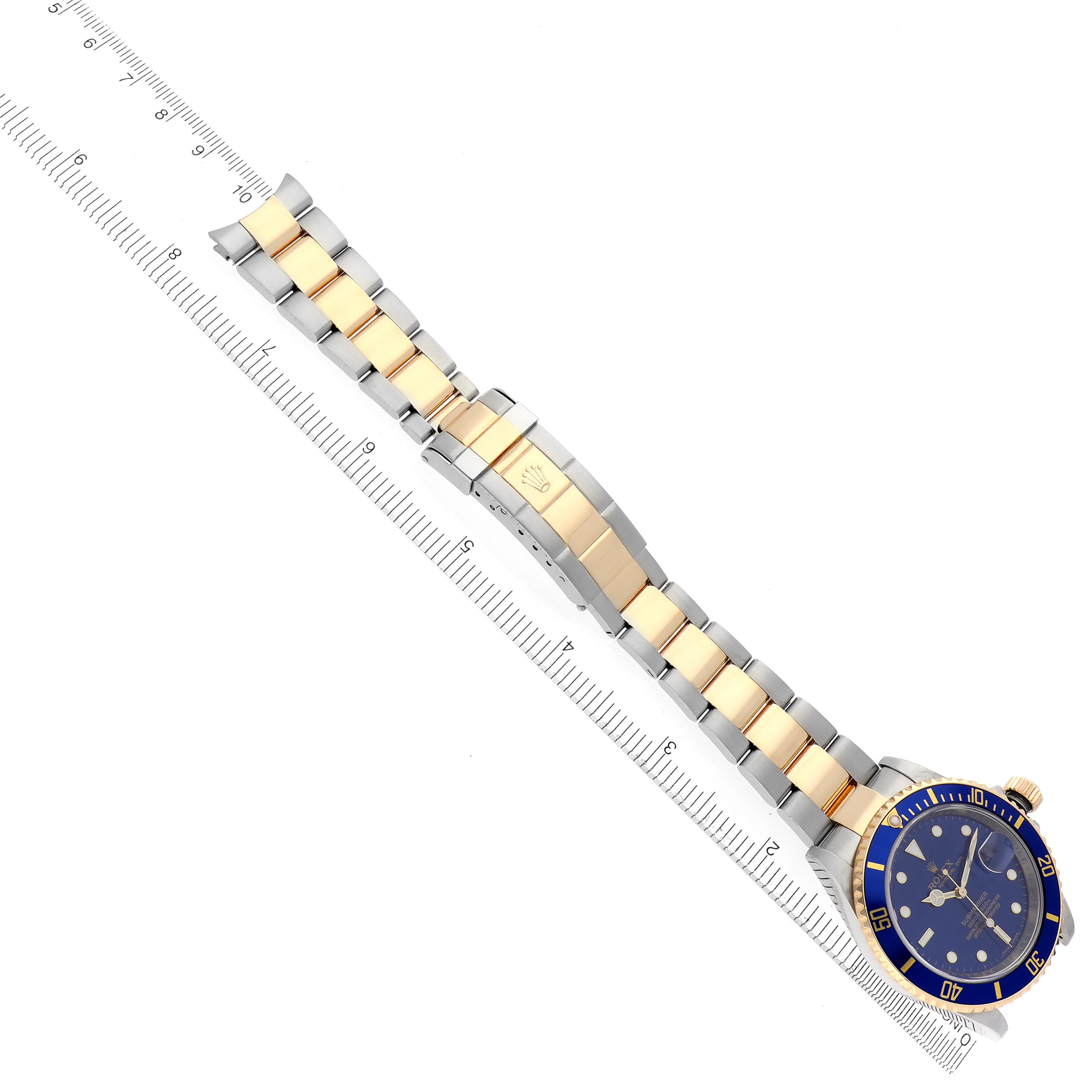 The image shows a Rolex Submariner 16613 Men
s Steel and Gold (two tone) Blue Dial 16613 Men
s Steel and Gold (two tone) Blue Dial watch face-up with a ruler alongside, displaying the bracelet and clasp.