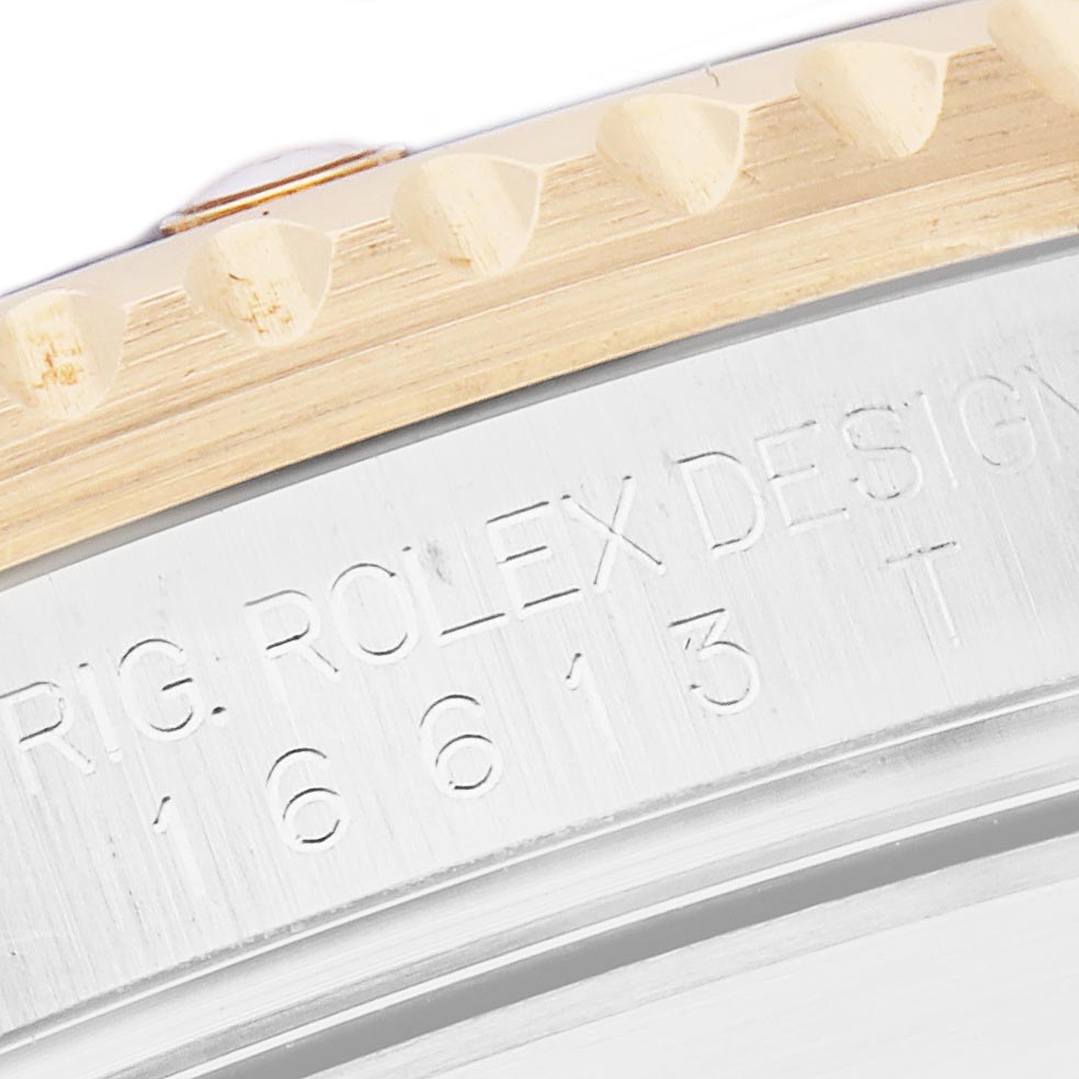 The image shows a close-up of a Rolex Submariner 16613 Men
s Steel and Gold (two tone) Blue Dial 16613 Men
s Steel and Gold (two tone) Blue Dial
s edge, focusing on the bezel and engraved model details.