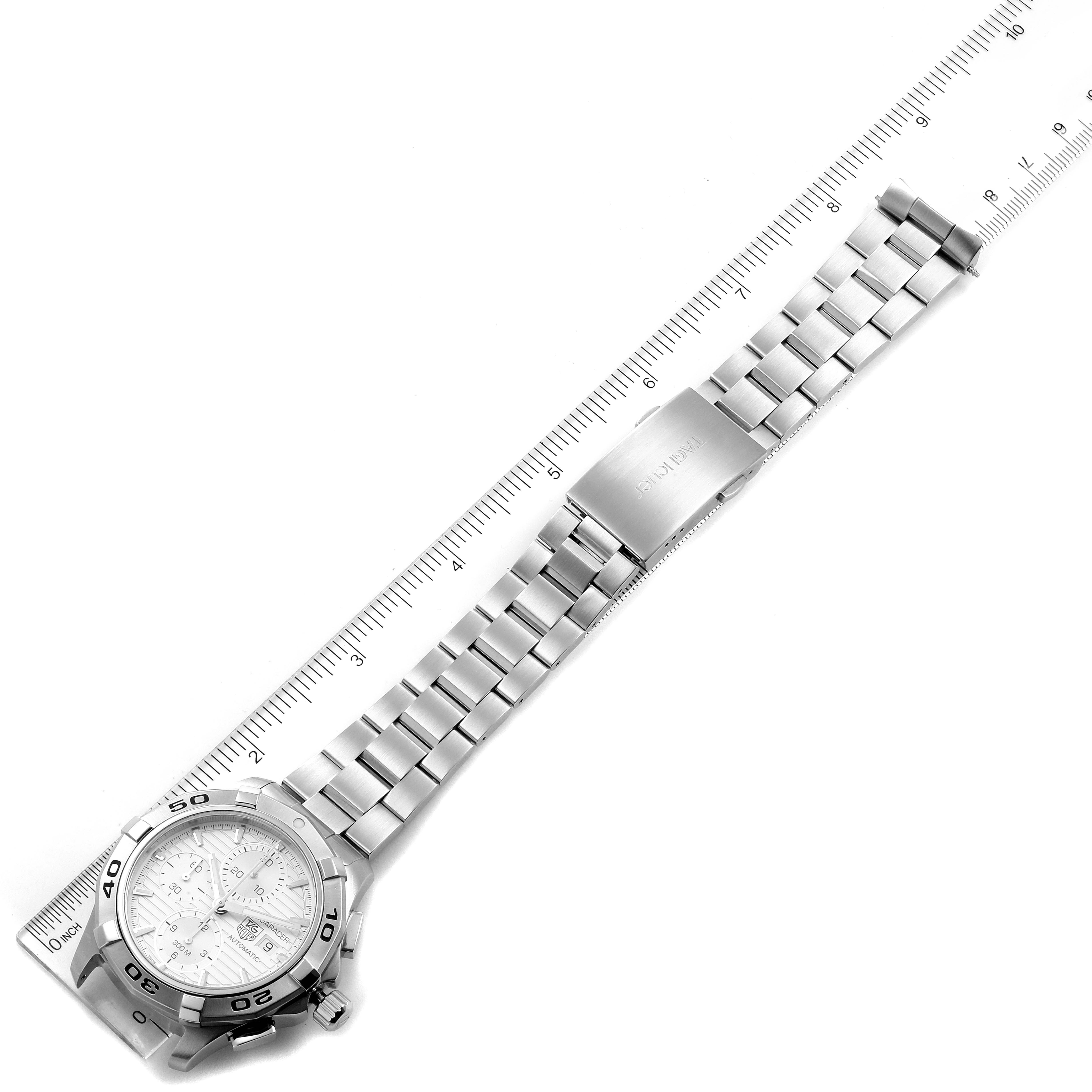 The image shows a top view of the Tag Heuer Aquaracer CAP2111.BA0833 Men's Stainless Steel Silver Dial CAP2111.BA0833 Men's Stainless Steel Silver Dial watch, highlighting its bracelet, clasp, and dial next to a ruler.