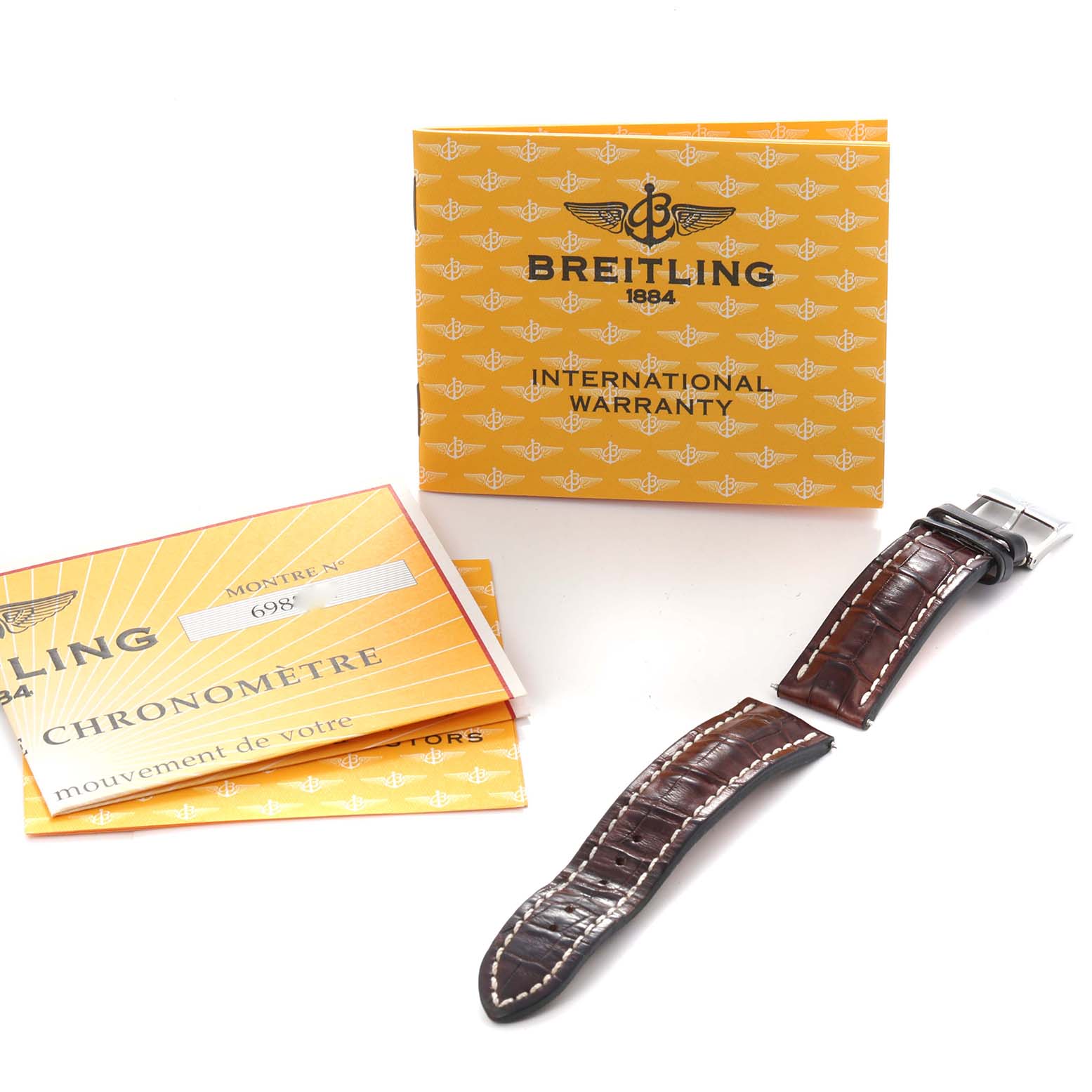 The image shows a leather strap and warranty booklet for a Breitling Windrider D1335512 Men
s Steel and Gold (two tone) Black Dial D1335512 Men
s Steel and Gold (two tone) Black Dial watch, viewed from above.