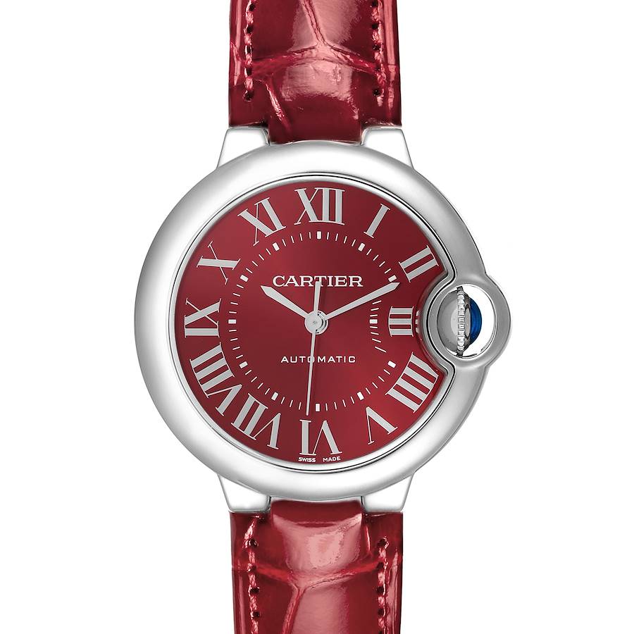 The Cartier Ballon Bleu watch is shown from a front angle, highlighting its red dial, Roman numerals, and metal case with a leather strap.