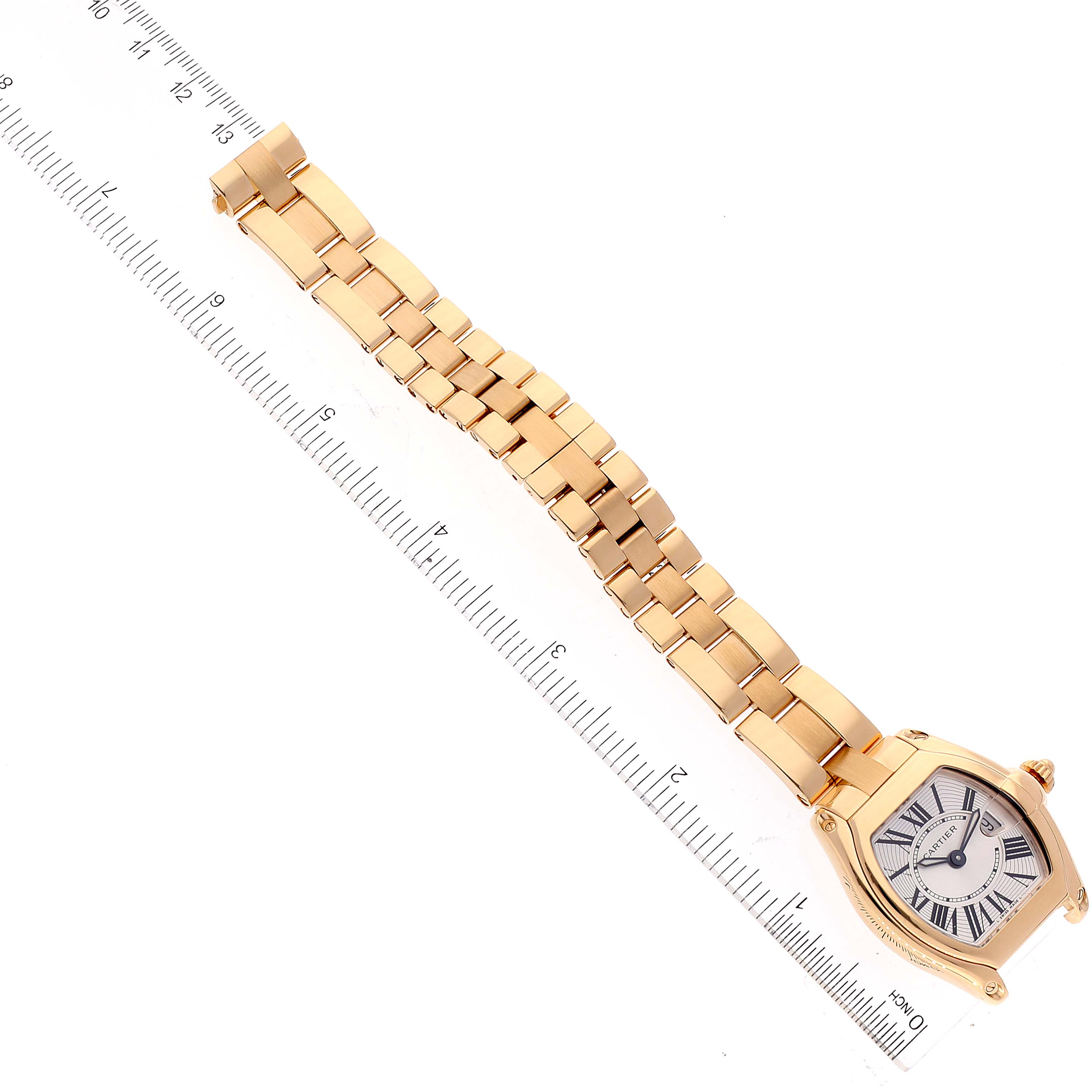 This image shows a Cartier Roadster W62018V1 Women
s Yellow Gold Silver Dial W62018V1 Women
s Yellow Gold Silver Dial watch laid flat beside a ruler, showcasing its face and bracelet.