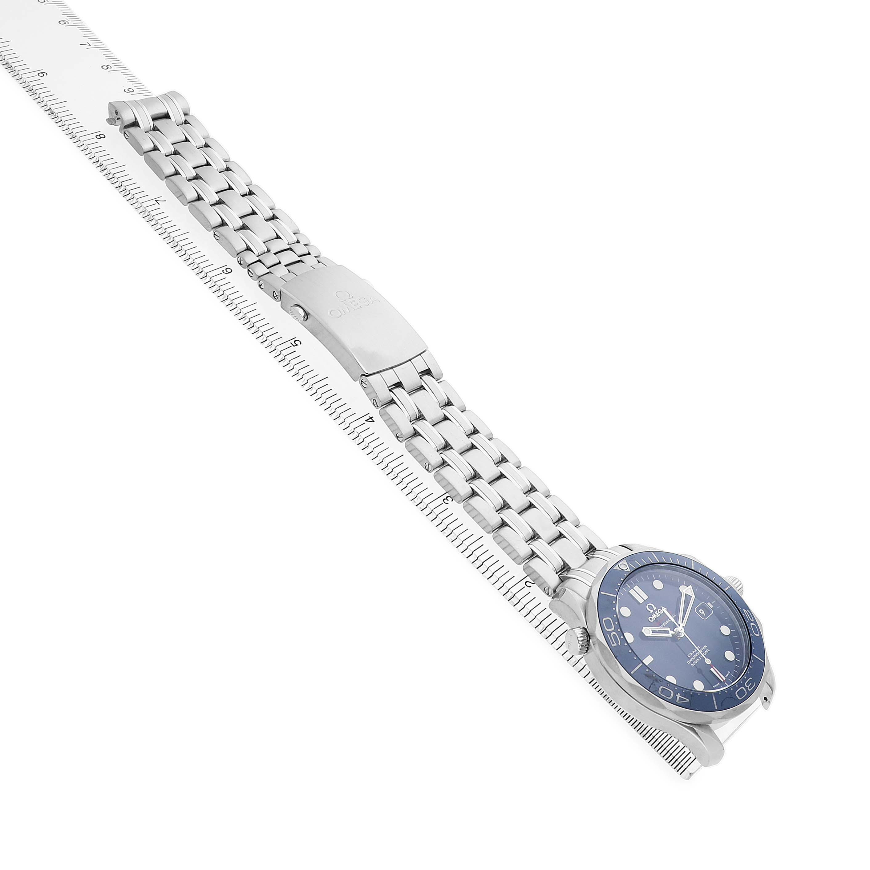 The Omega Seamaster 212.30.41.20.03.001 Men's Stainless Steel Blue Dial watch is shown at an angle displaying the dial, bracelet, and clasp laid alongside a ruler.
