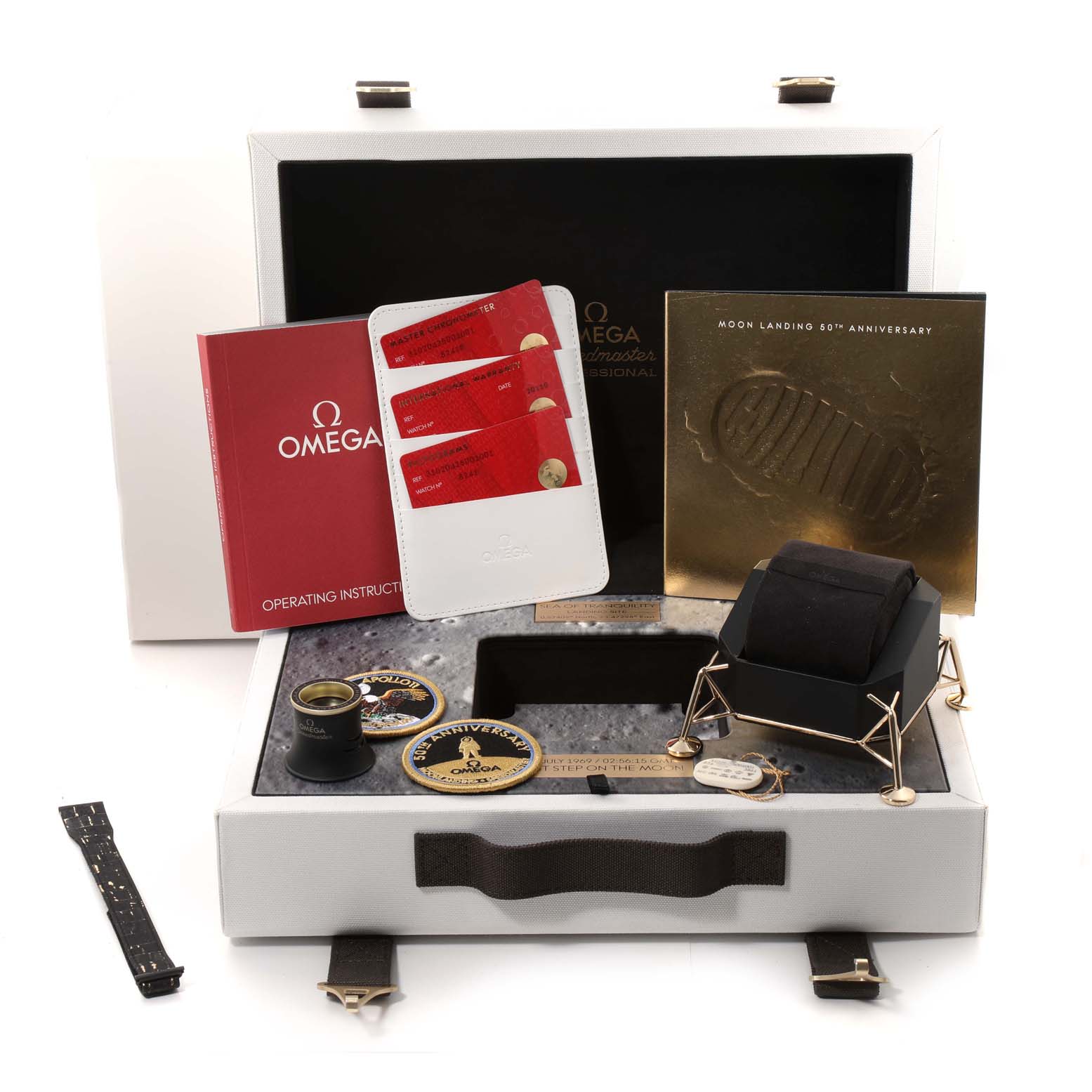 The Omega Speedmaster 310.20.42.50.01.001 Men's Stainless Steel Grey Dial 310.20.42.50.01.001 Men's Stainless Steel Grey Dial is displayed with accessories like booklets, patches, a magnifier, a strap, a stand, and an Apollo-themed box.