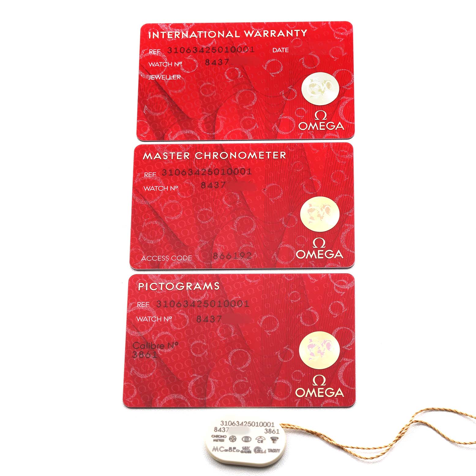 This image shows warranty and certification cards for an Omega Speedmaster 310.63.42.50.10.001 Men's Yellow Gold Black Dial, along with a hang tag, all viewed from above.