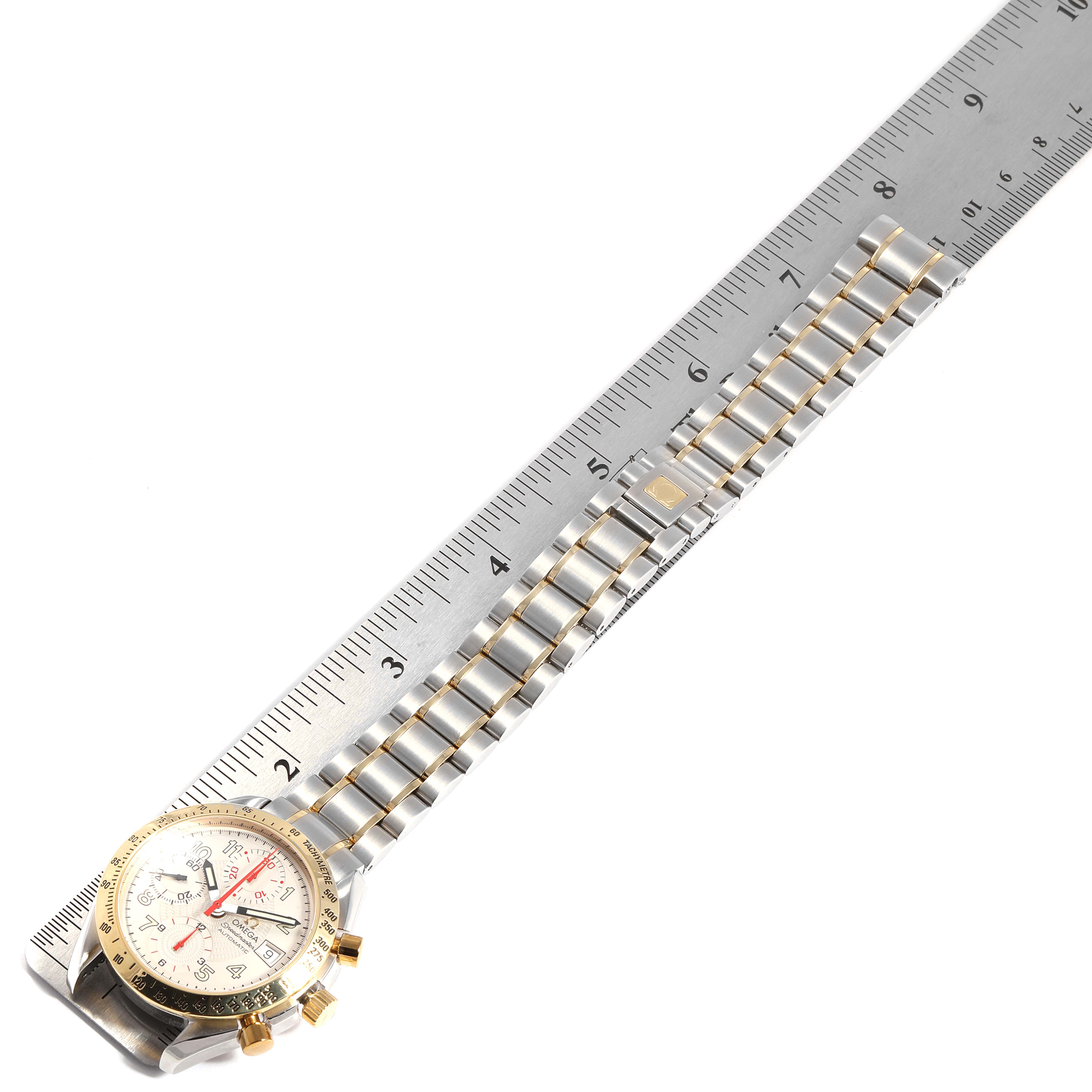 The Omega Speedmaster 3313.33.00 Men's Steel and Gold (two tone) White Dial 3313.33.00 Men's Steel and Gold (two tone) White Dial watch is positioned sideways, showing its full bracelet and a portion of the face, next to a ruler for measurement.