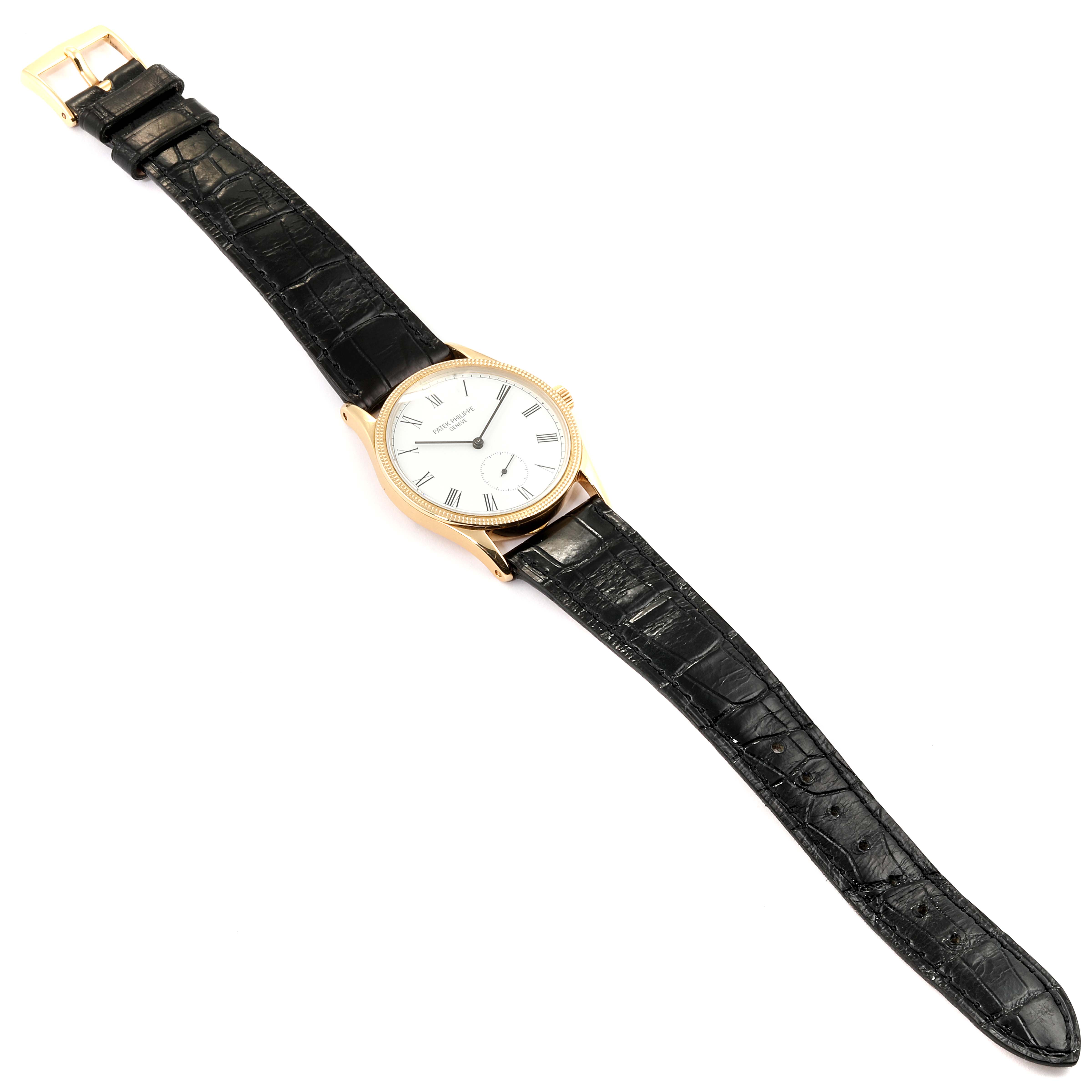 The Vintage Patek Philippe watch is shown from a top-down angle, featuring a black leather strap and a round gold case with a white dial.