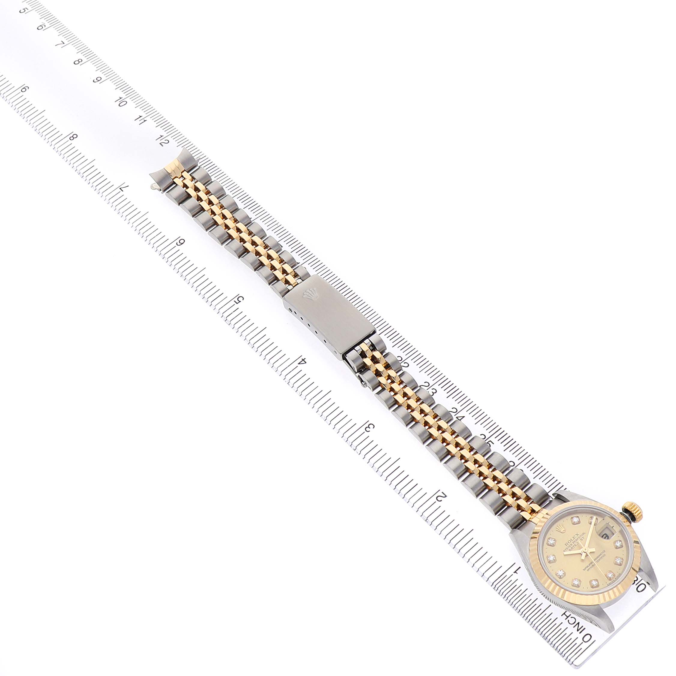The Rolex Datejust 79173 Women's Stainless Steel Champagne Dial watch is shown from a top-down angle, highlighting the dial and bracelet alongside a ruler for scale.