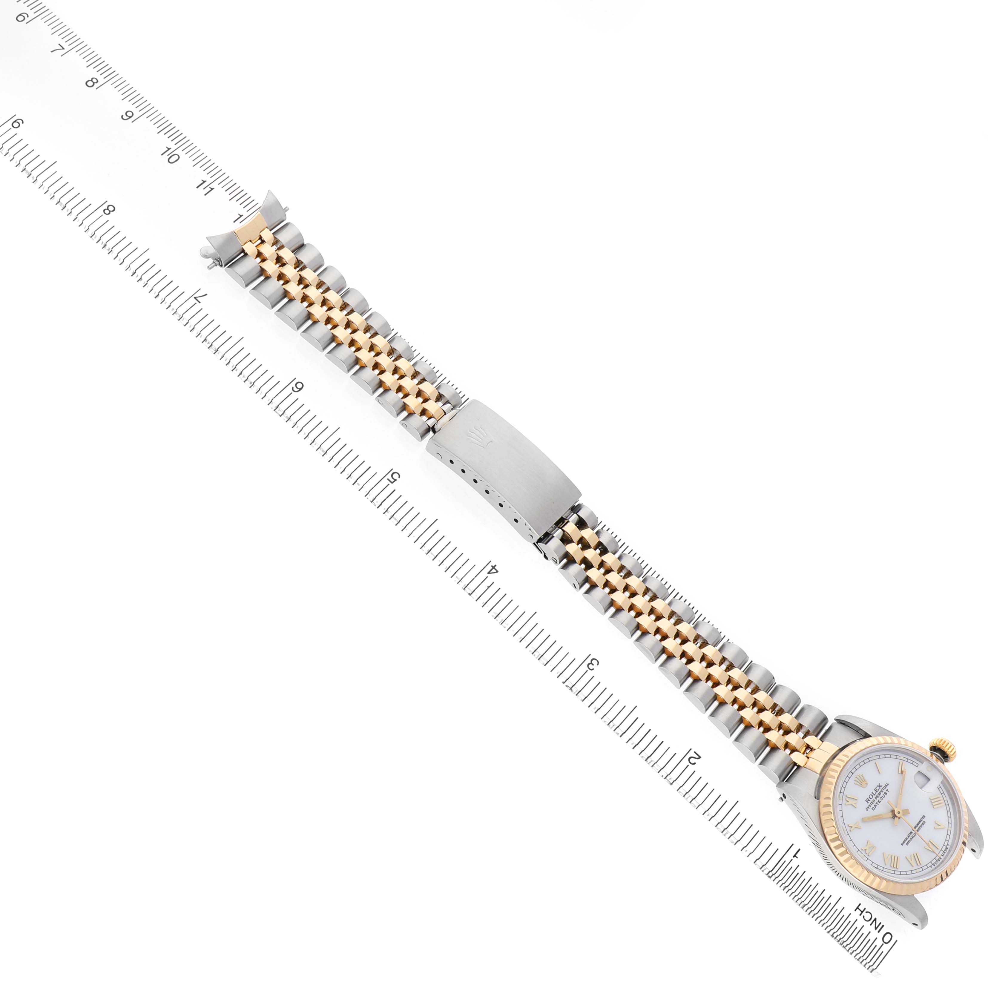 The image shows a Rolex Mid-Size 68273 Women's Steel and Gold (two tone) White Dial watch from above, highlighting the bracelet, clasp, and part of the watch face next to a ruler.
