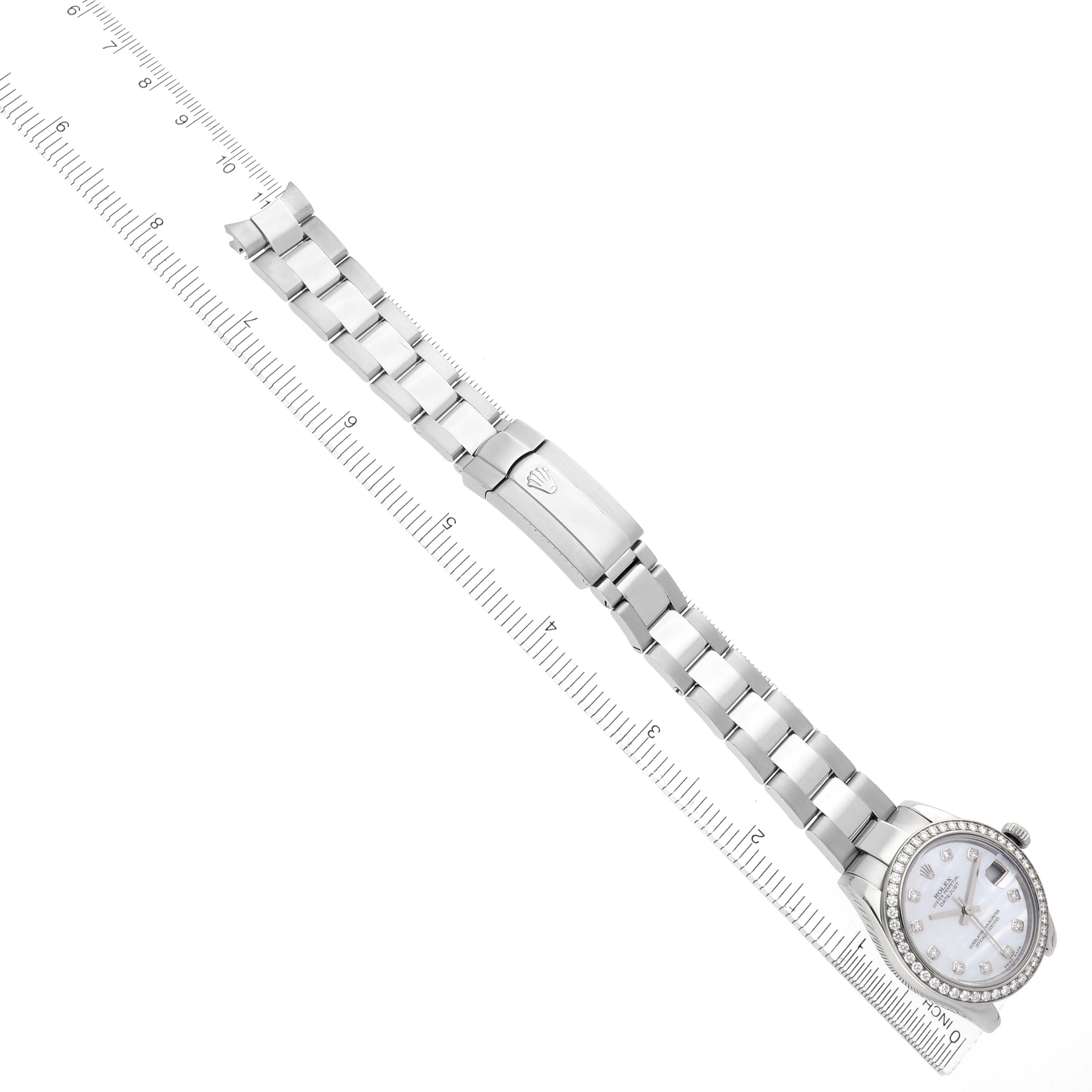 The image shows a Rolex Mid-Size 178384 Women
s Stainless Steel Mother of Pearl Dial 178384 Women
s Stainless Steel Mother of Pearl Dial watch laid flat, displaying the dial, bracelet, and clasp, alongside a measuring ruler.