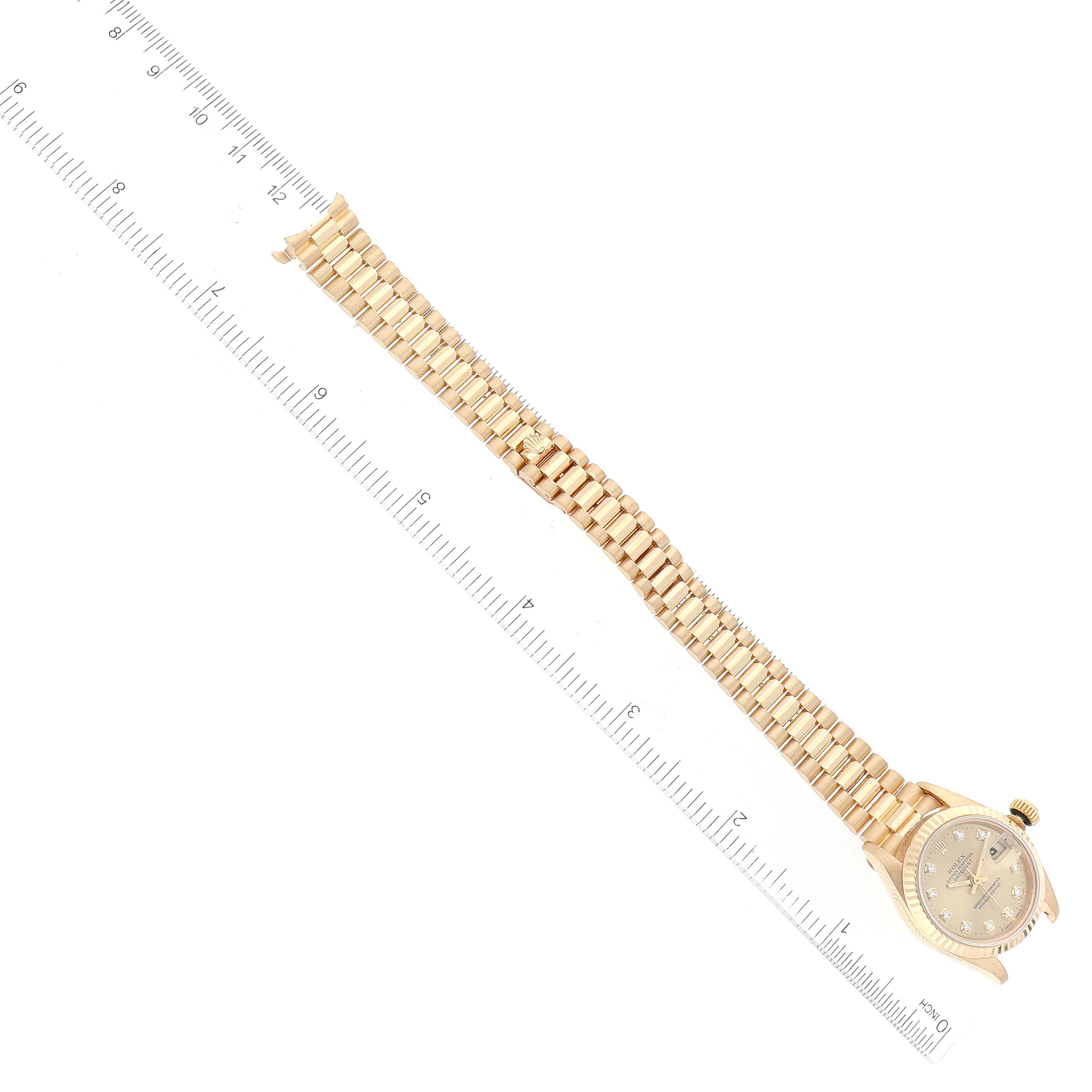The image shows a Rolex President 69178 Women
s Yellow Gold Champagne Dial 69178 Women
s Yellow Gold Champagne Dial model watch laid flat with its face and full bracelet visible, beside a ruler for scale.