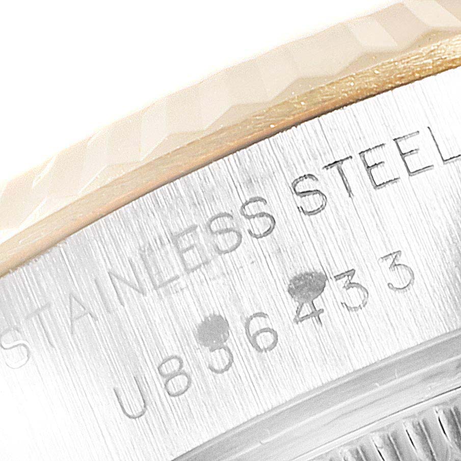 The image shows a close-up of the side of a Rolex Datejust 69173  Women
s Steel and Gold (two tone) Champagne Dial 69173  Women
s Steel and Gold (two tone) Champagne Dial watch, highlighting the engraved serial number and part of the fluted bezel.
