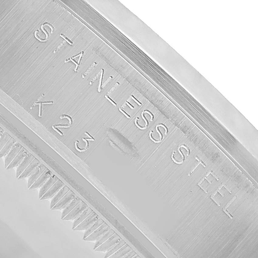 The image shows a close-up of a stainless steel case edge of a Rolex Mid-Size 77080 Women's Stainless Steel Blue Dial watch, focusing on the engravings.