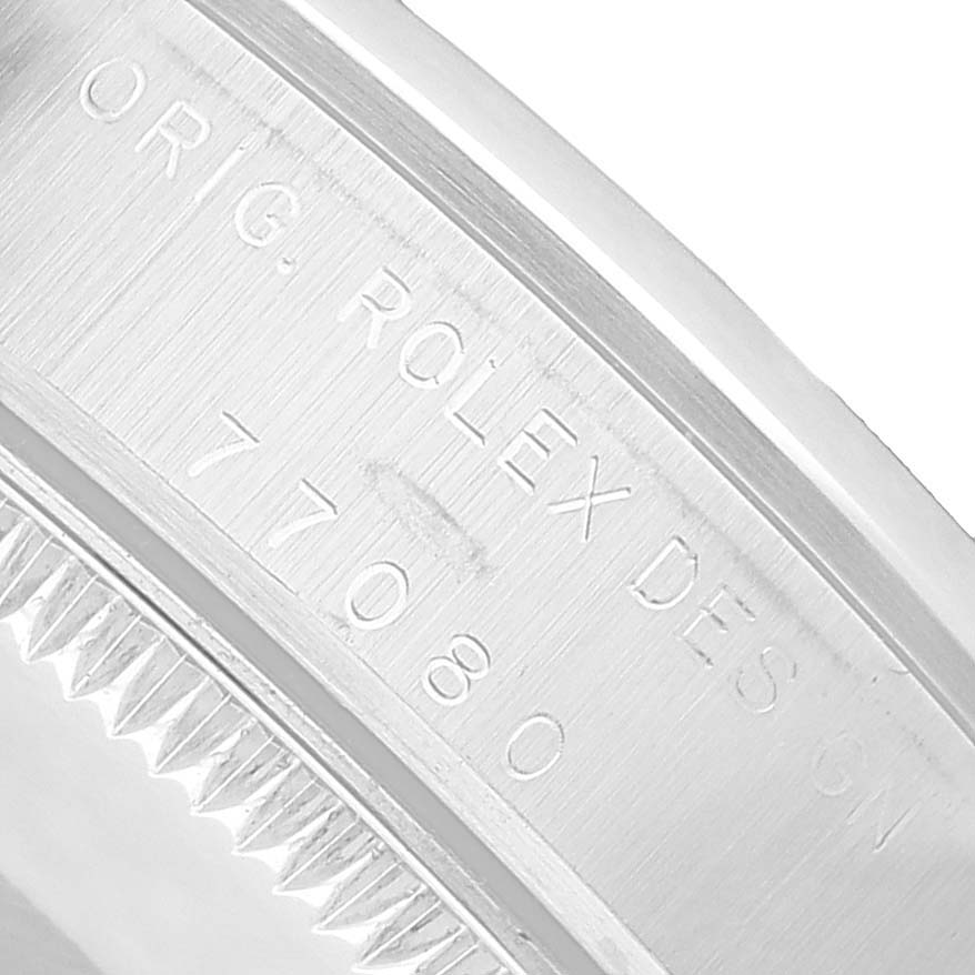 The image shows a close-up of the etched edge of a Rolex Oyster Perpetual 77080 Women's Stainless Steel Black Dial watch case, highlighting the "ORIG. ROLEX DESIGN" engraving.