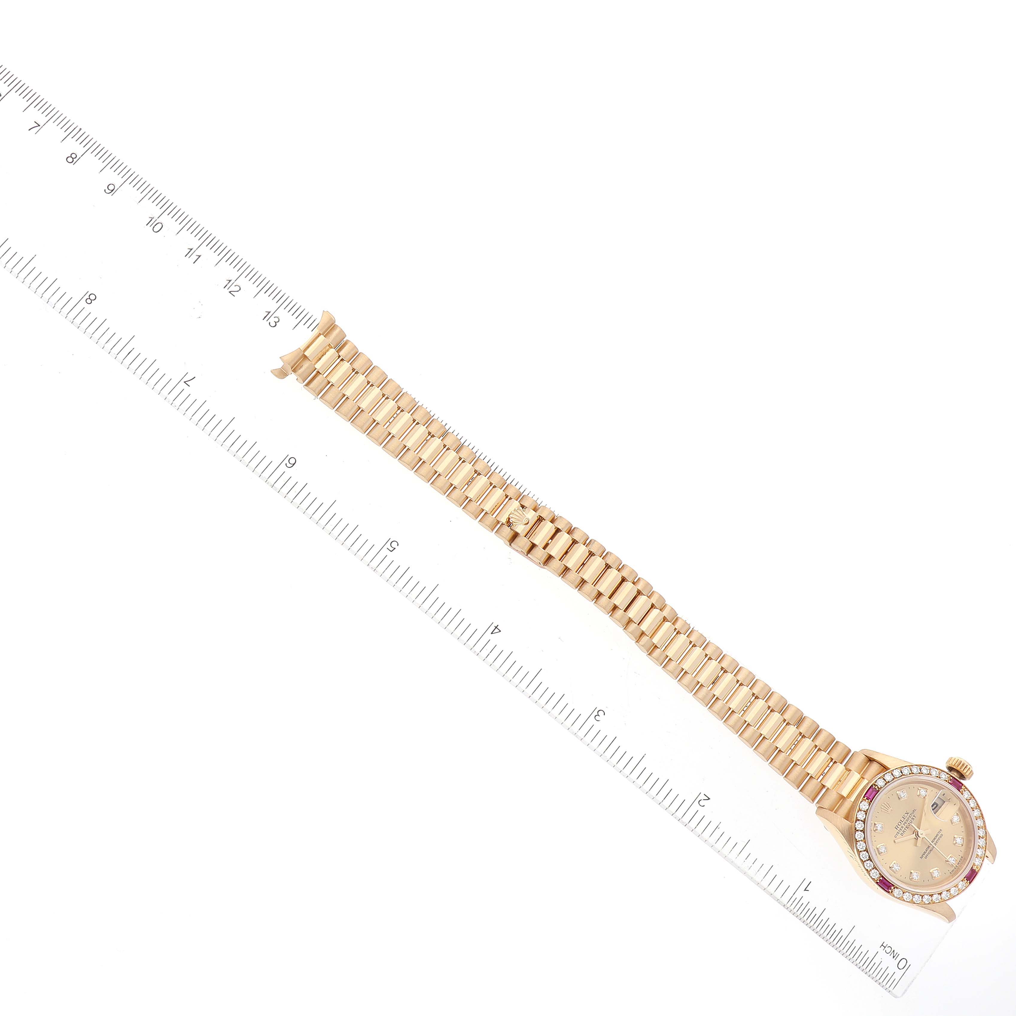 The image shows a Rolex President 79068 Women
s Yellow Gold Champagne Dial 79068 Women
s Yellow Gold Champagne Dial model watch laid flat next to a ruler, displaying the face and entire bracelet.