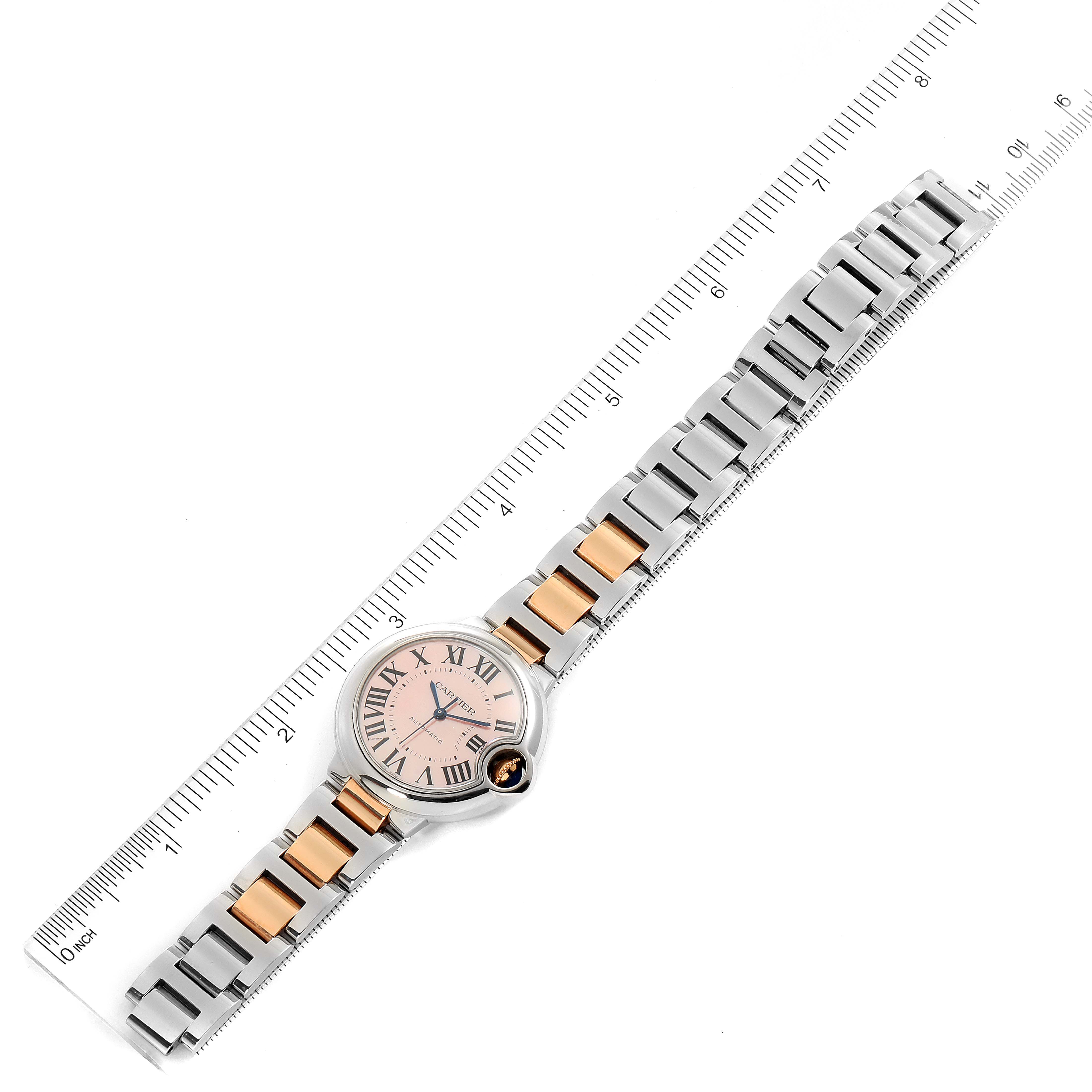 The Cartier Ballon Bleu W6920098 Women's Steel and Gold (two tone) Mother of Pearl Dial W6920098 Women's Steel and Gold (two tone) Mother of Pearl Dial watch is shown from a top-down angle, displaying the face, bracelet, and a ruler for scale.