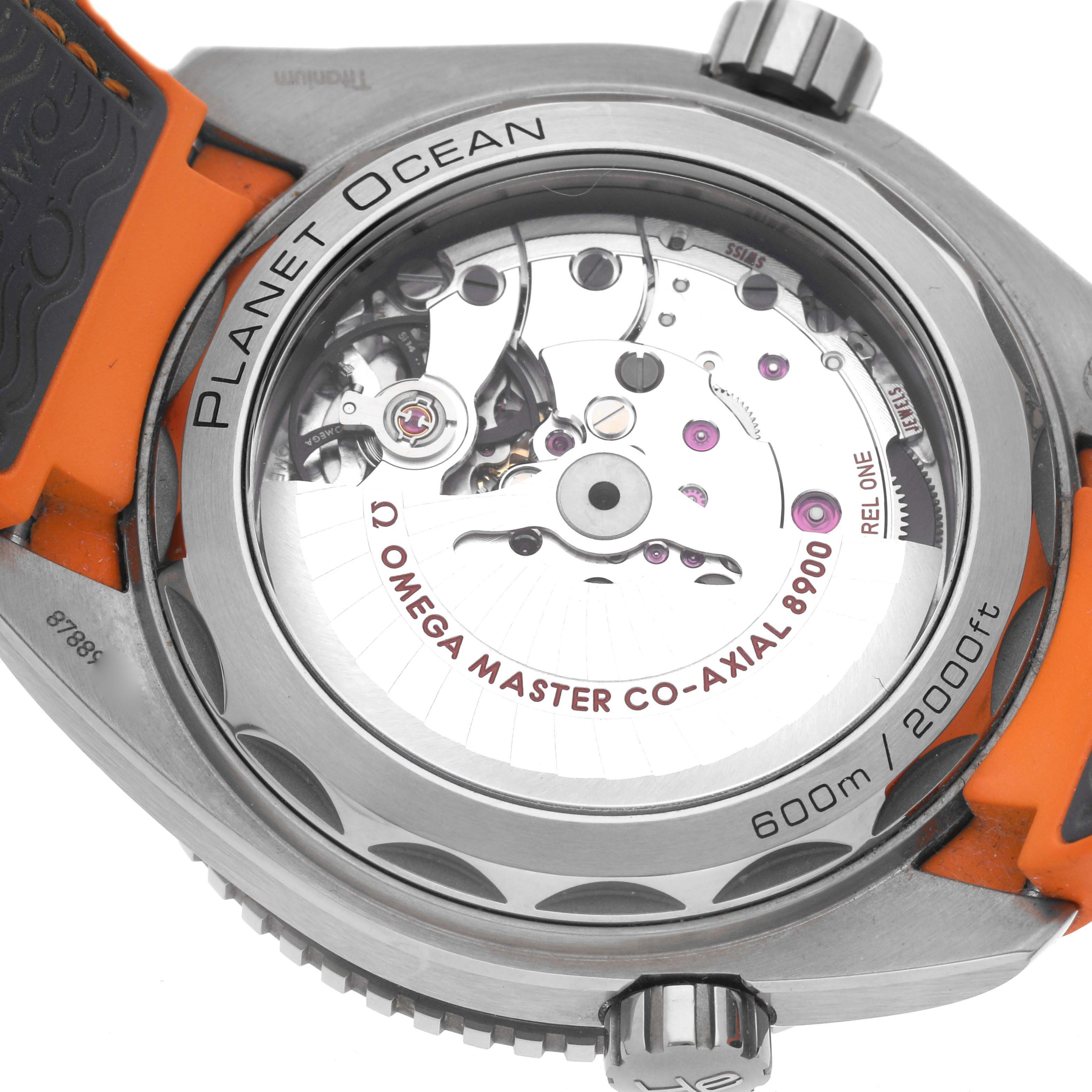 The image shows the back of the Omega Planet Ocean 215.92.44.21.99.001 Men
s Titanium Grey Dial 215.92.44.21.99.001 Men
s Titanium Grey Dial watch, highlighting its movement and orange strap.