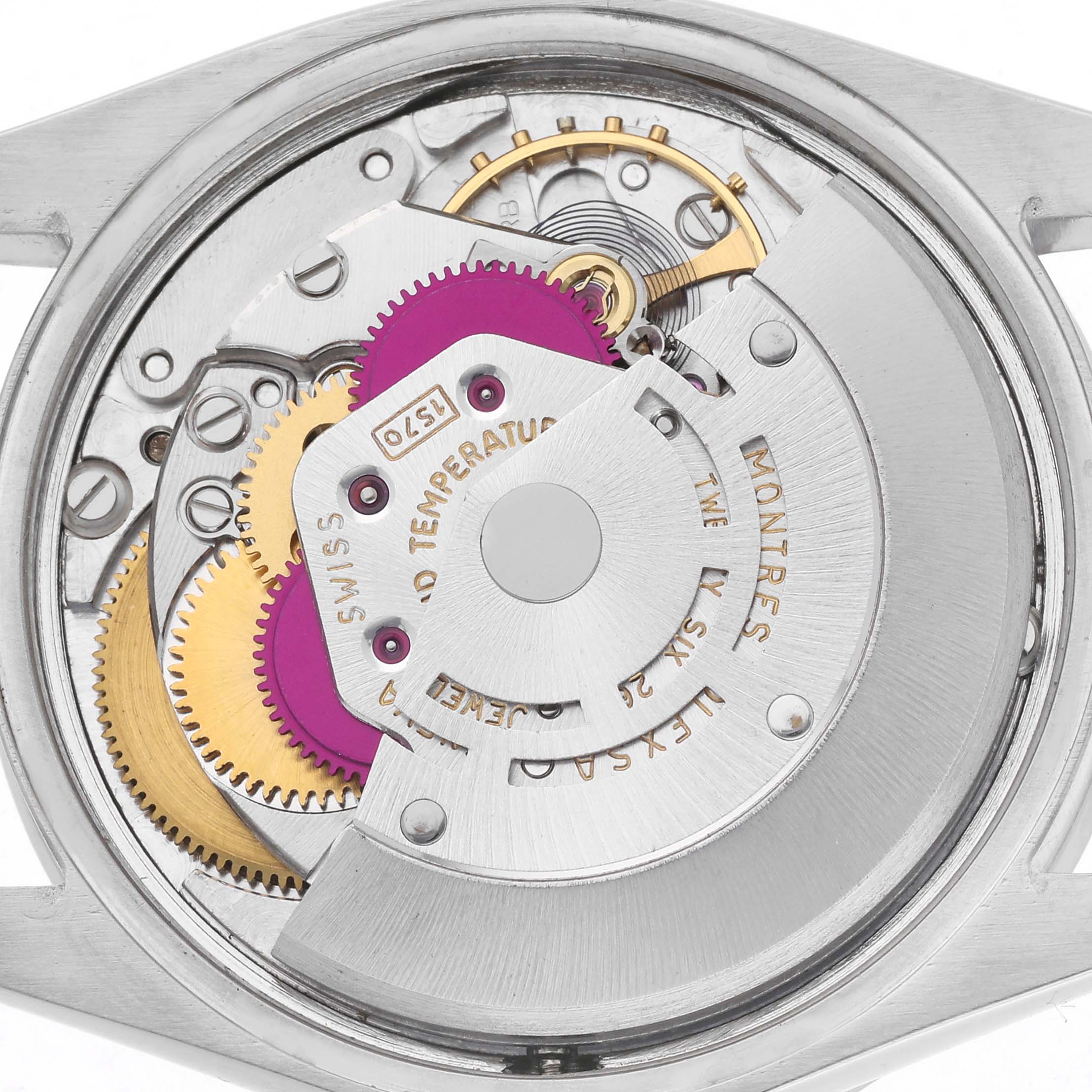 The image shows the internal movement of a Rolex Date model, featuring gears and rotor mechanism.