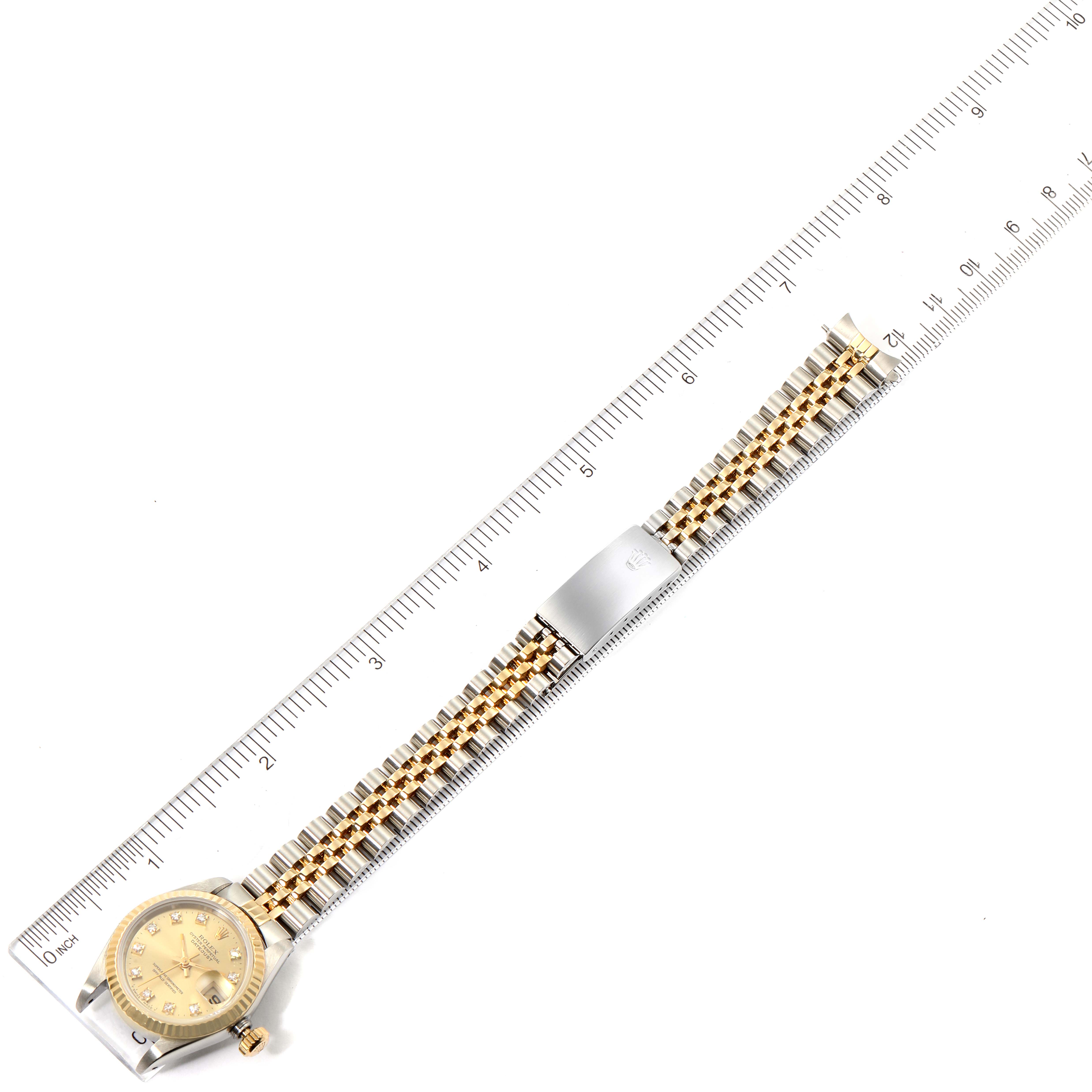 The Rolex Datejust 69173 Women's Steel and Gold (two tone) Champagne Dial 69173 Women's Steel and Gold (two tone) Champagne Dial watch is shown from an overhead angle, with the dial, crown, and bracelet clearly visible, next to a ruler.