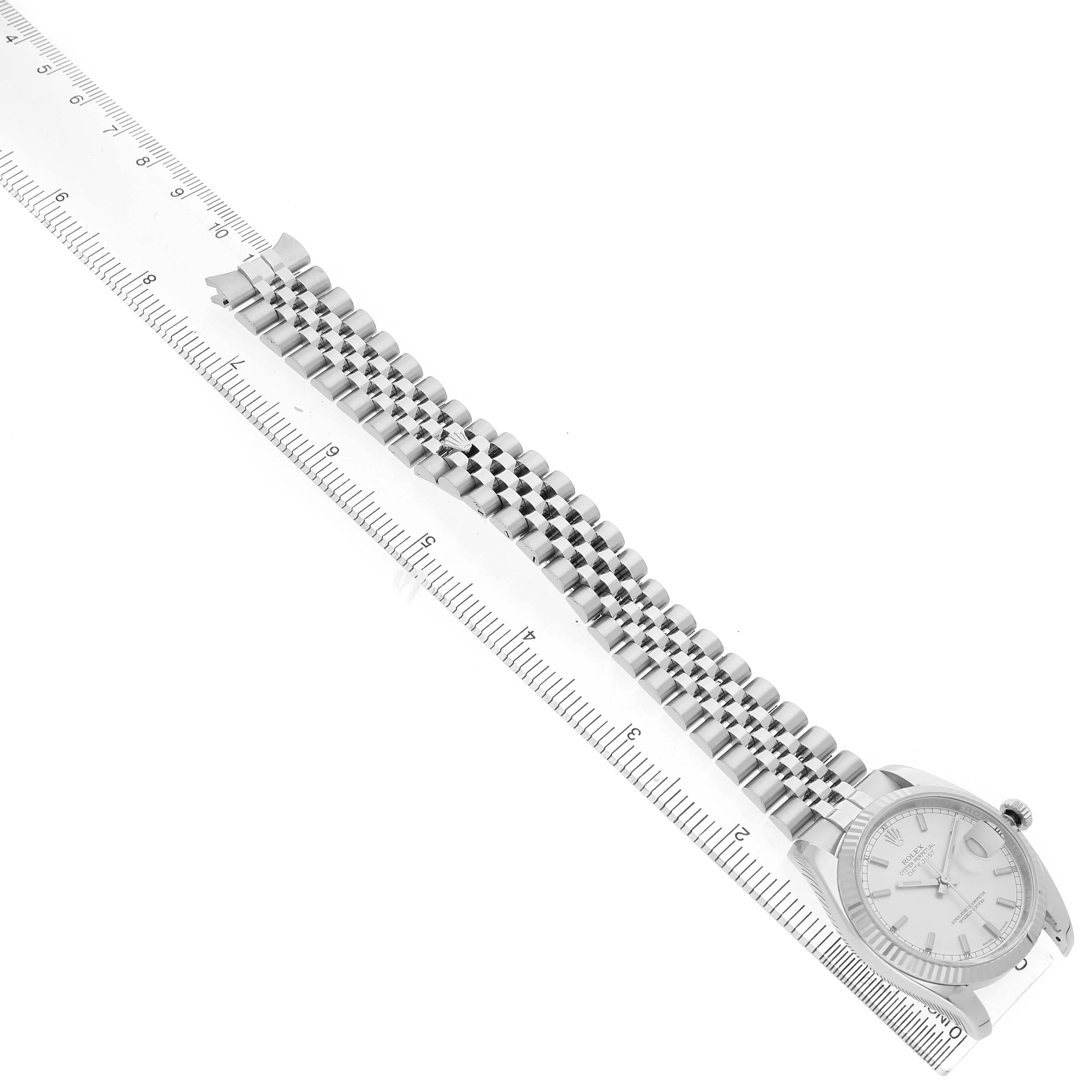 The Rolex Datejust 116234 Men's Stainless Steel Silver Dial watch is shown from a top-down angle, displaying the face, bracelet, and a ruler for scale.