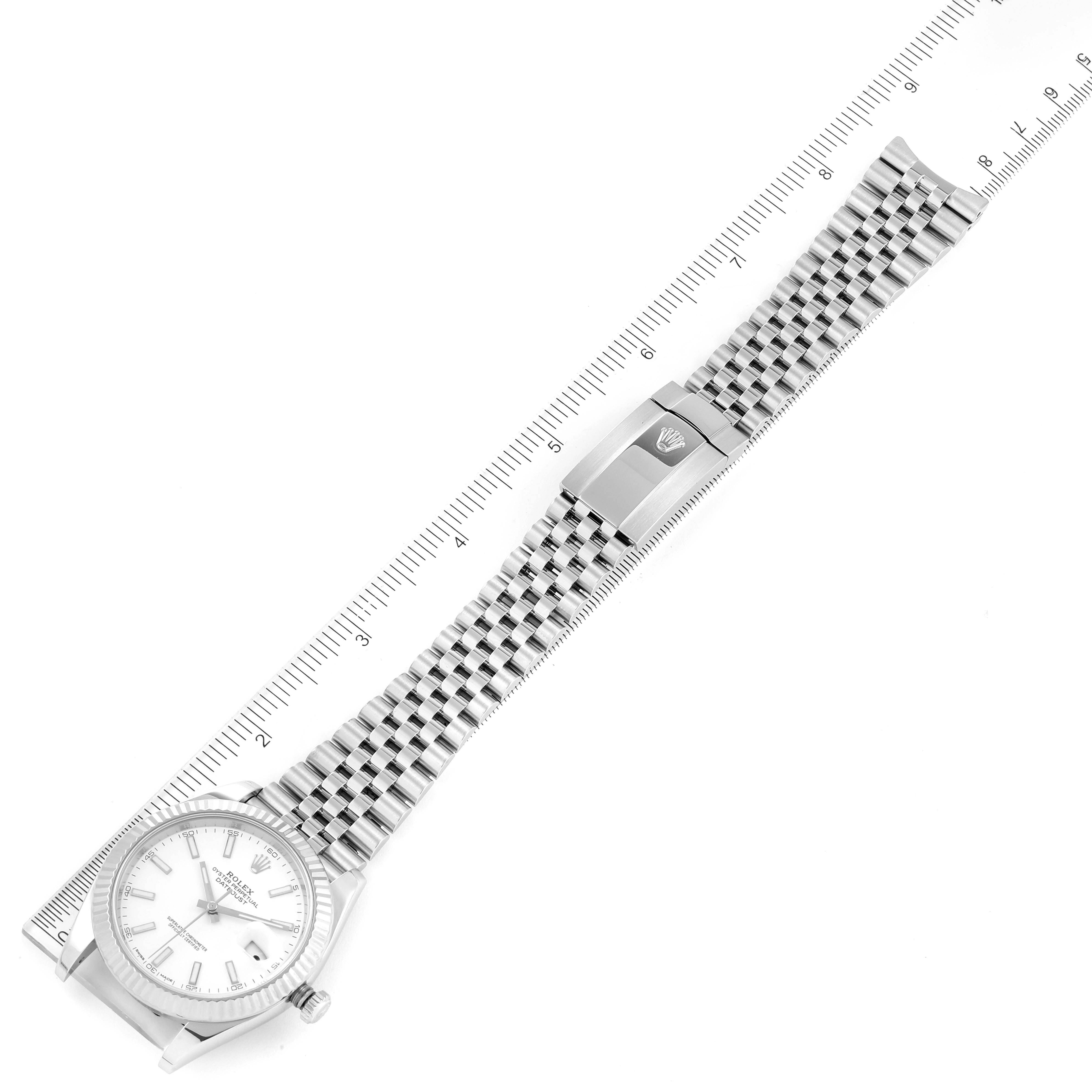The image shows an overhead view of a Rolex Datejust 41 126334 Men's Stainless Steel White Dial 126334 Men's Stainless Steel White Dial, highlighting the full bracelet and clasp alongside a ruler for scale.