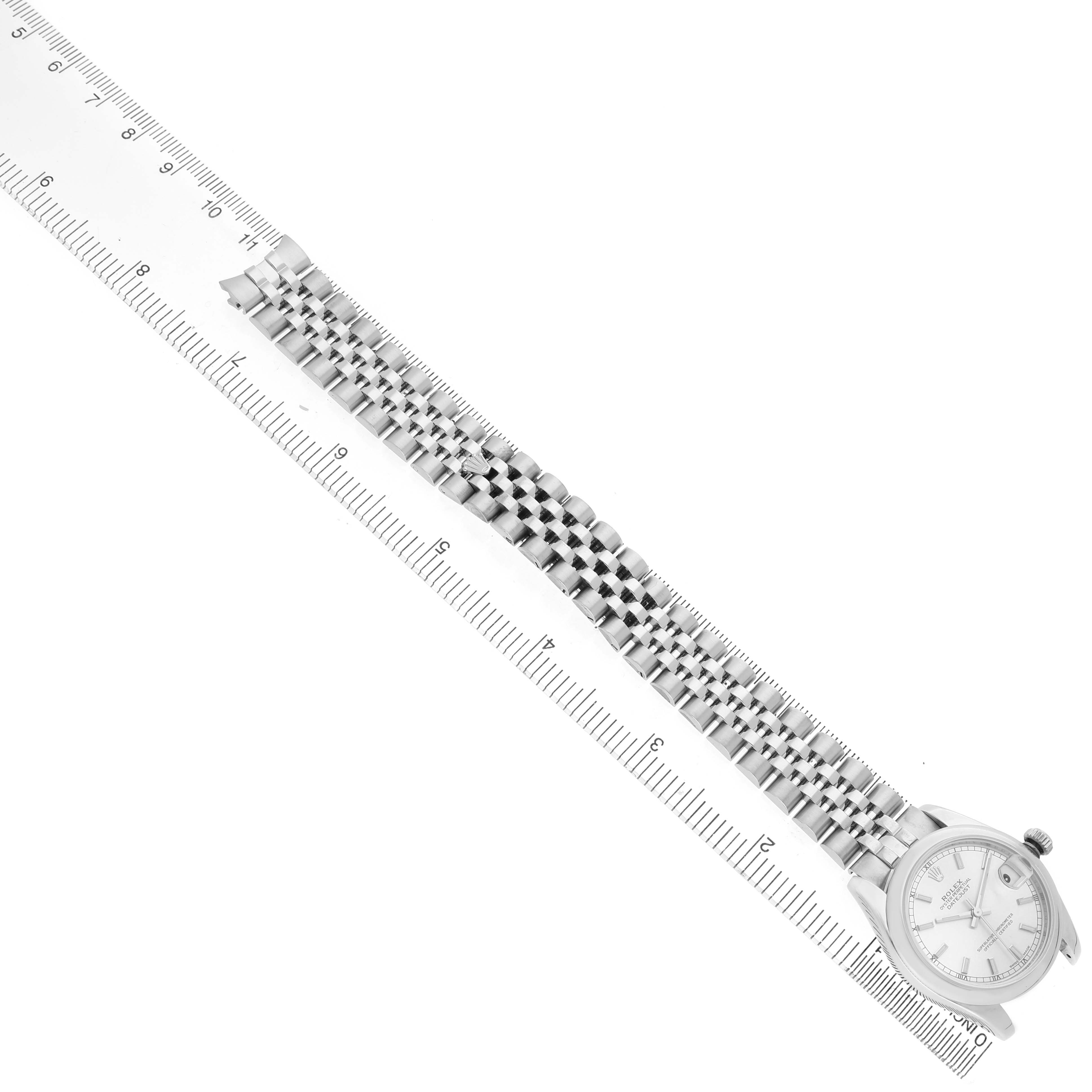 The Rolex Datejust 178240 Women's Stainless Steel Silver Dial watch is shown from a top angle, displaying the full bracelet alongside a ruler for scale.