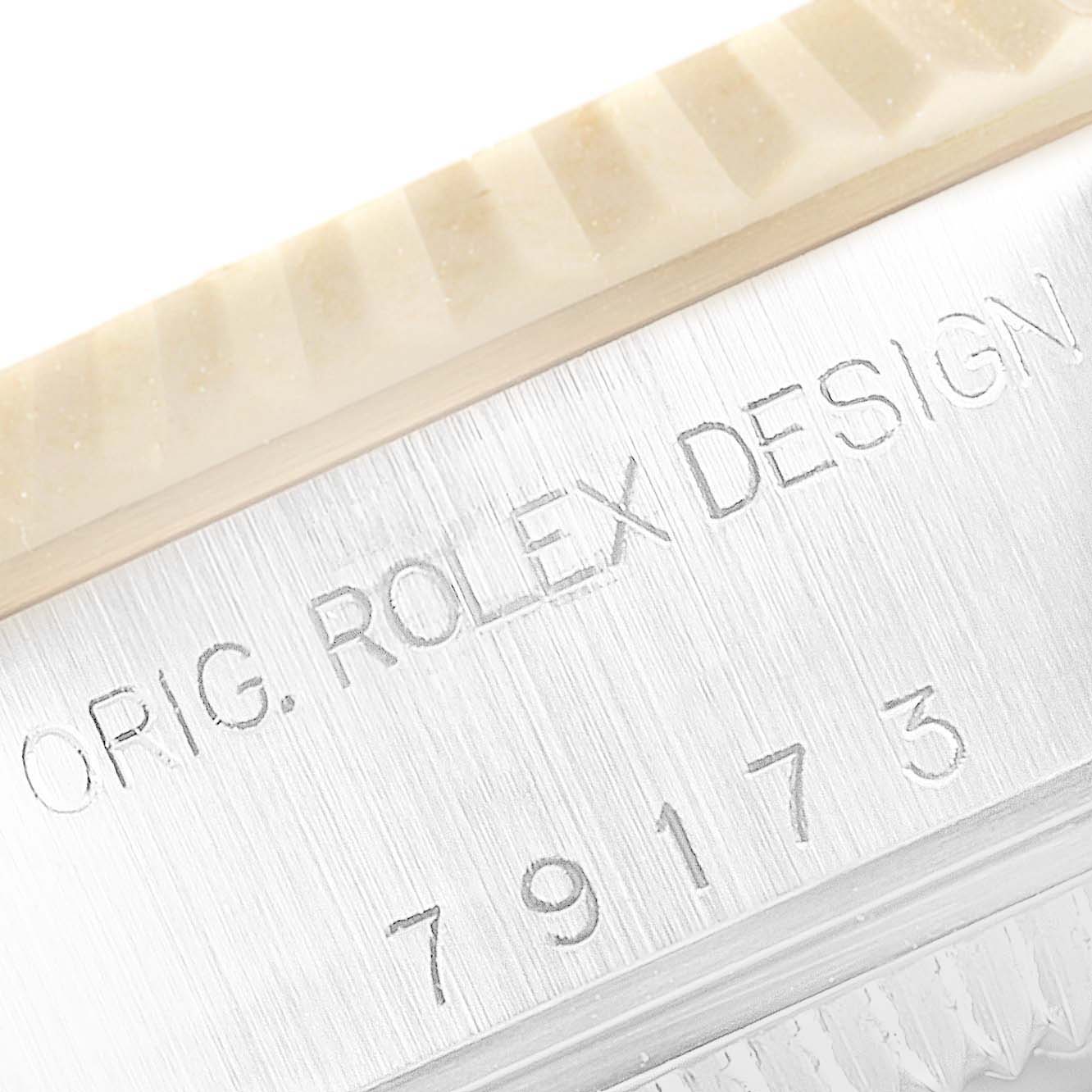 This image shows a close-up of the side of a Rolex Datejust 79173 Women
s Steel and Gold (two tone) Beige Dial 79173 Women
s Steel and Gold (two tone) Beige Dial watch, featuring part of the bezel and engraved serial number.