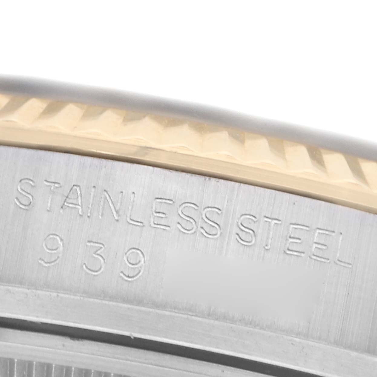 The image shows a close-up of the side of a Rolex Datejust 16013 Men
s Steel and Gold (two tone) Champagne Dial 16013 Men
s Steel and Gold (two tone) Champagne Dial watch, highlighting the engraved "Stainless Steel" on the case edge.