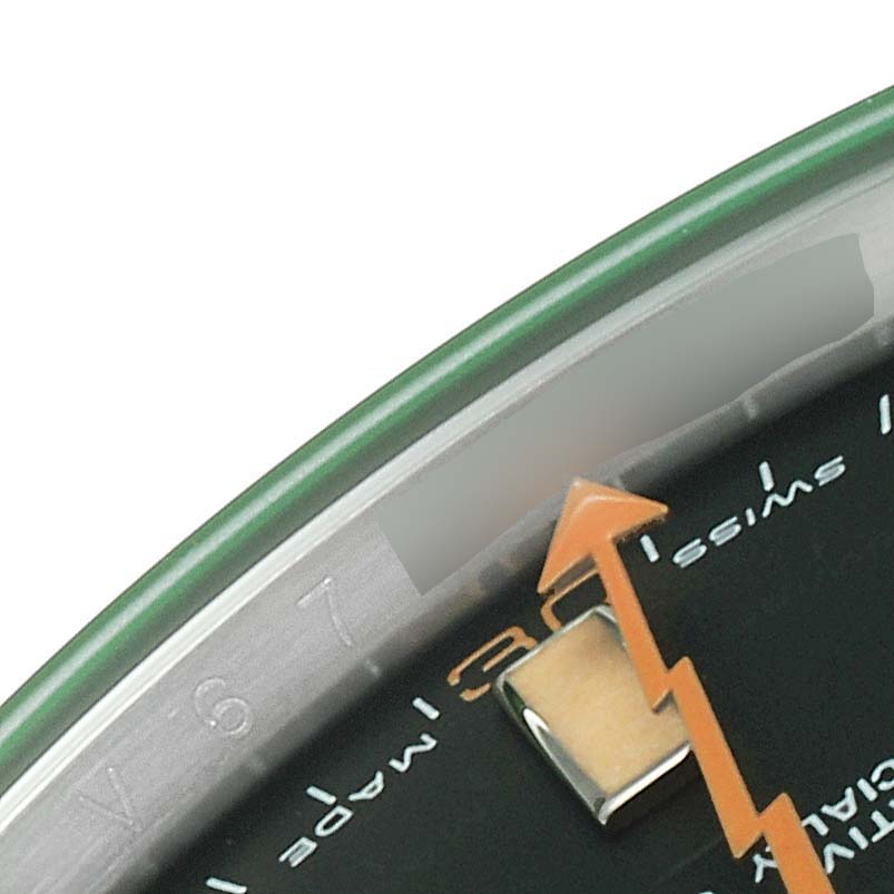 The image shows a close-up of the Rolex Milgauss 116400V Men
s Stainless Steel Black Dial 116400V Men
s Stainless Steel Black Dial watch face, highlighting part of the green bezel, orange lightning bolt second hand, and partial numerals.